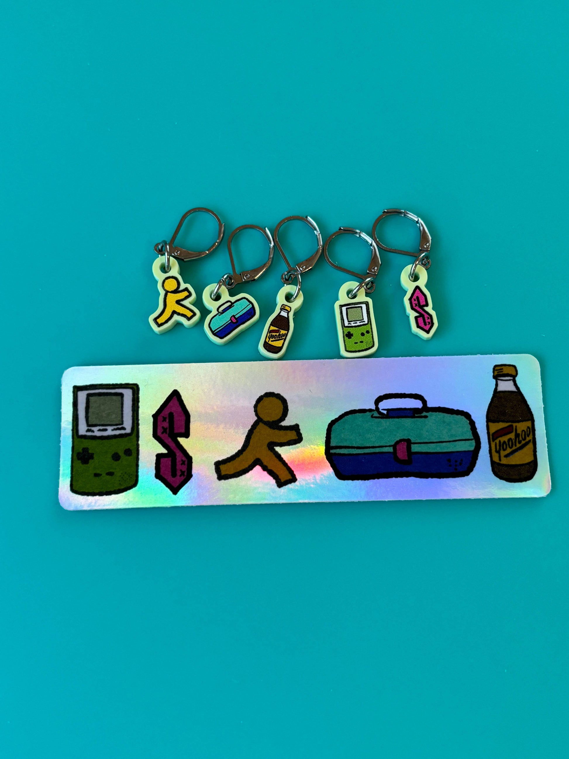 nostalgic 90s kid knitting accessories holographic tag with five stitch marker charms Game Boy running dollar sign lunchbox
