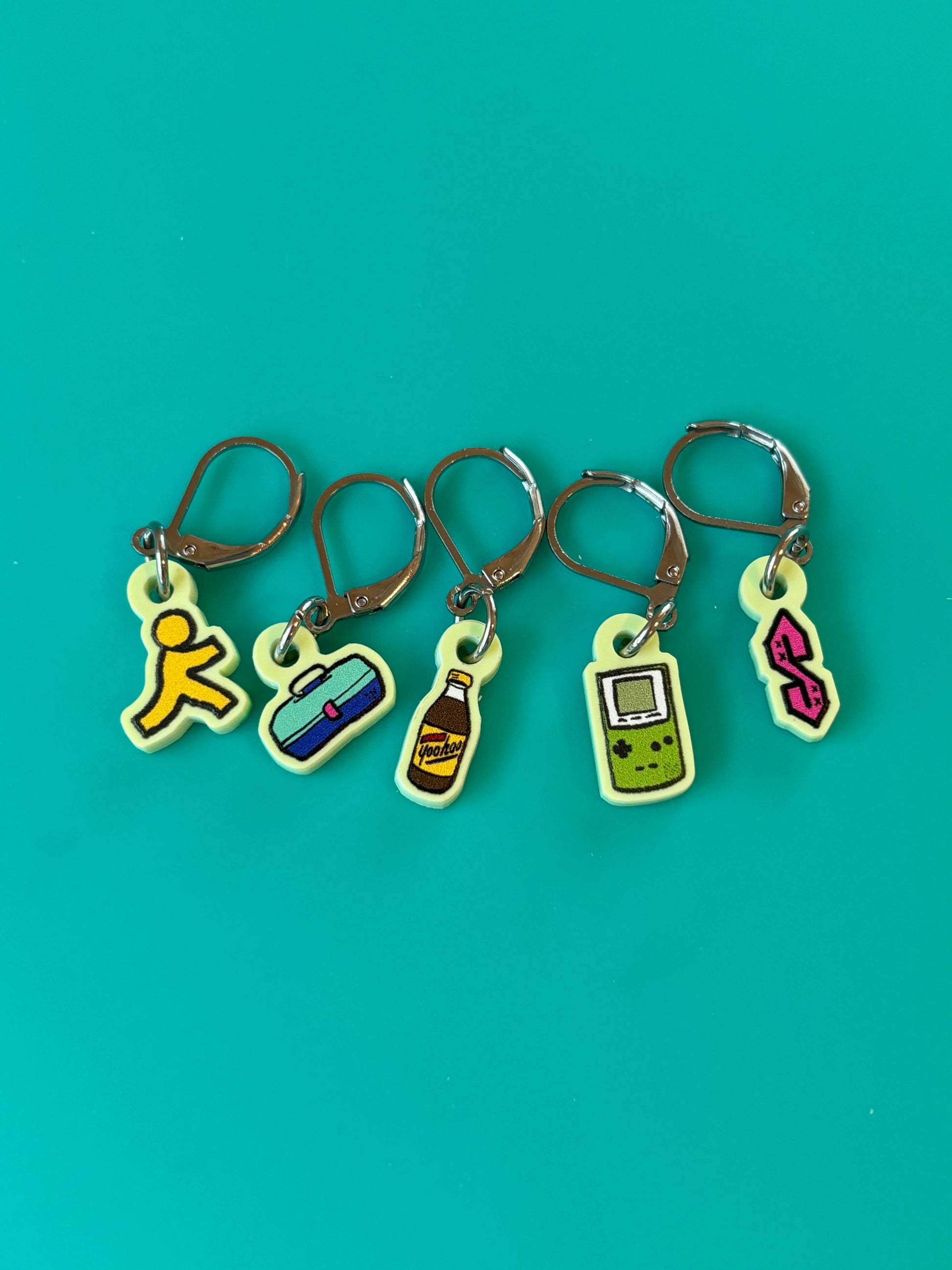 Comma Craft Co nostalgic 90s kid knitting accessories five lime stitch markers with Game Boy, soda, cassette, Tamagotchi on teal