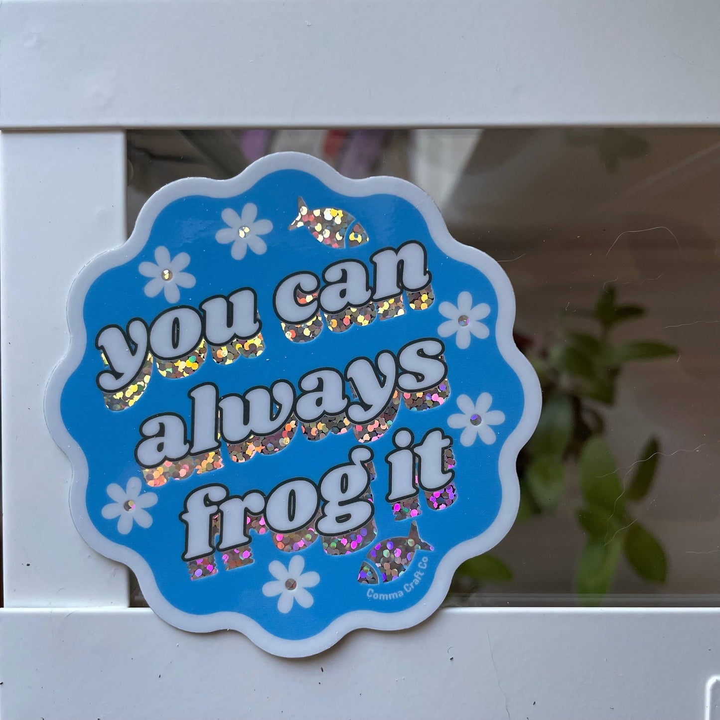 Blue scalloped Comma Craft Co sticker with holographic text and flowers reading knitting sticker you can always frog it.