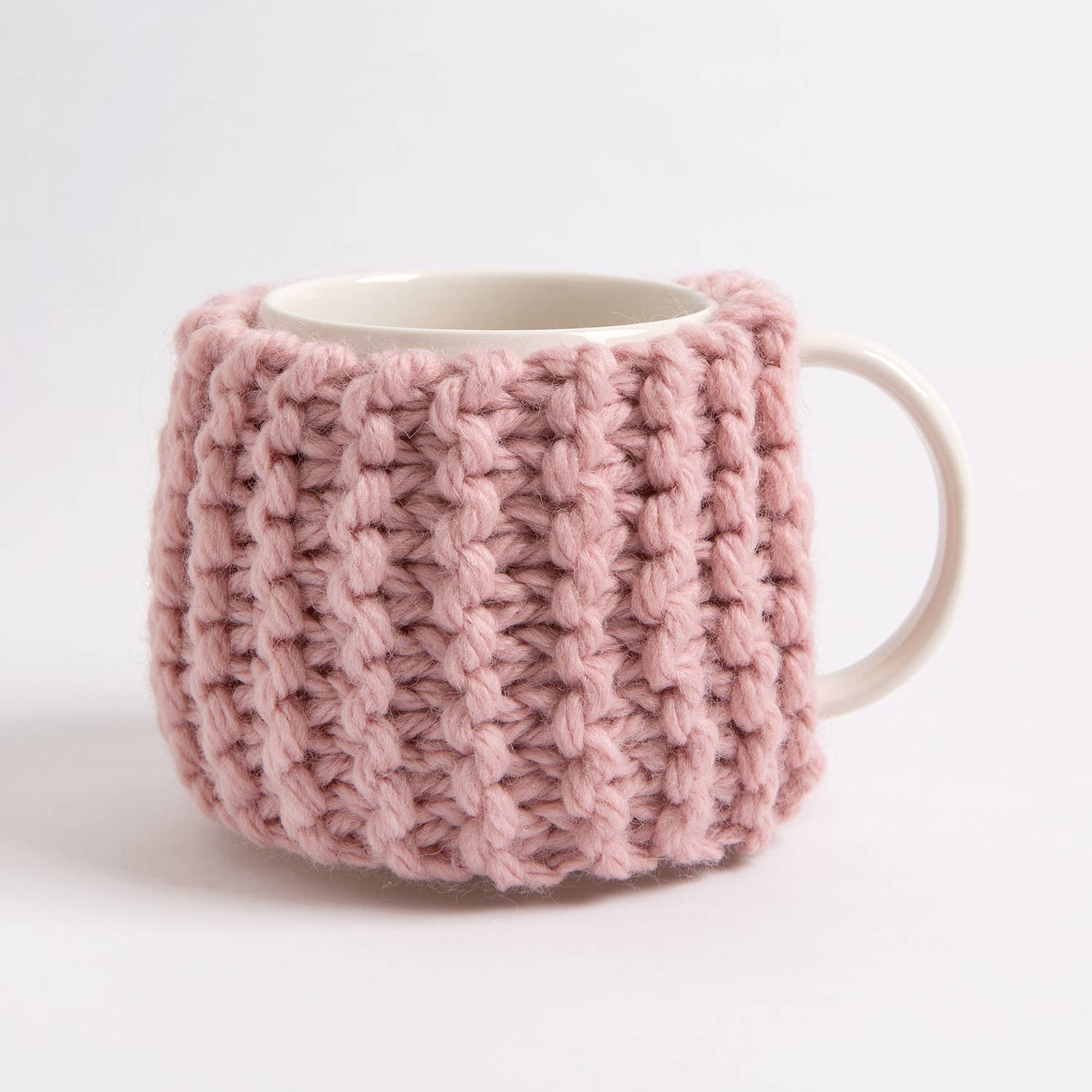 Pink chunky ribbed cup cozy on white mug showing knit stitch detail beginner knitting kit for cup cozy