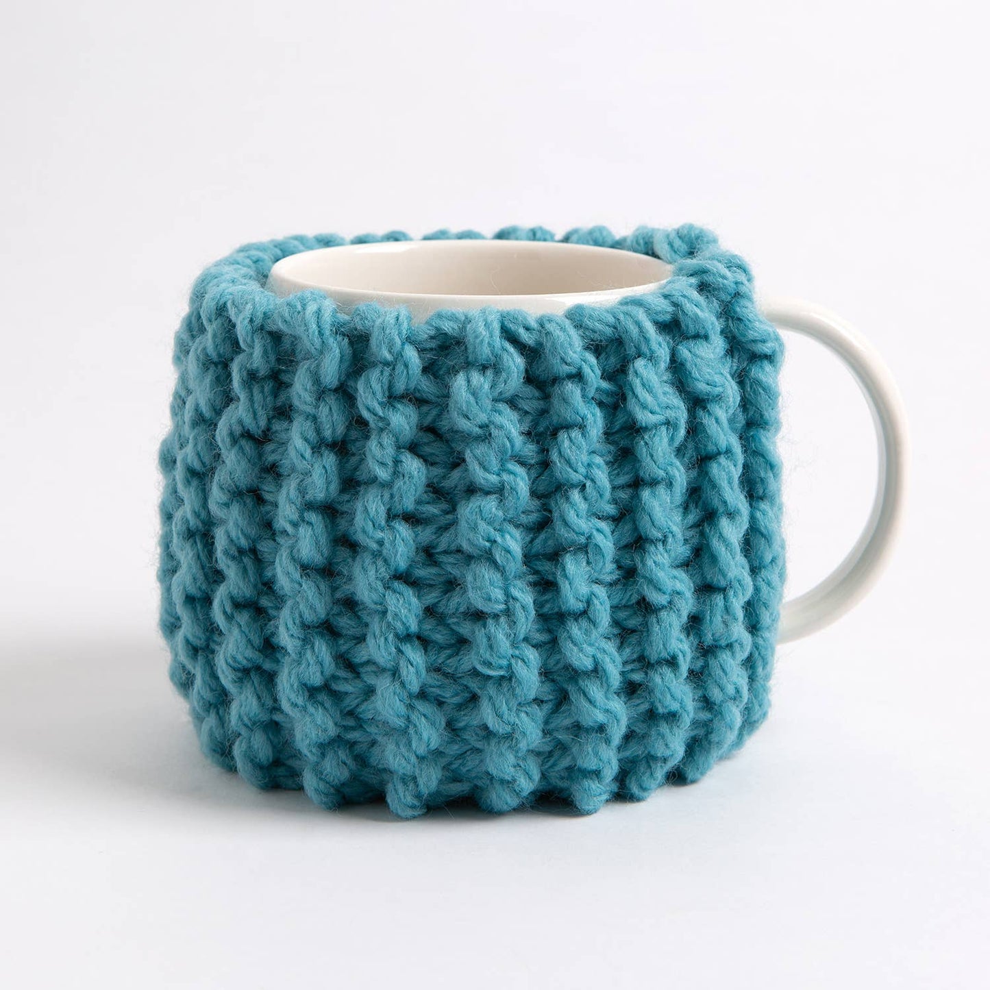 Teal chunky ribbed mug cozy on white ceramic mug from Wool Couture Company beginner knitting kit for cup cozy