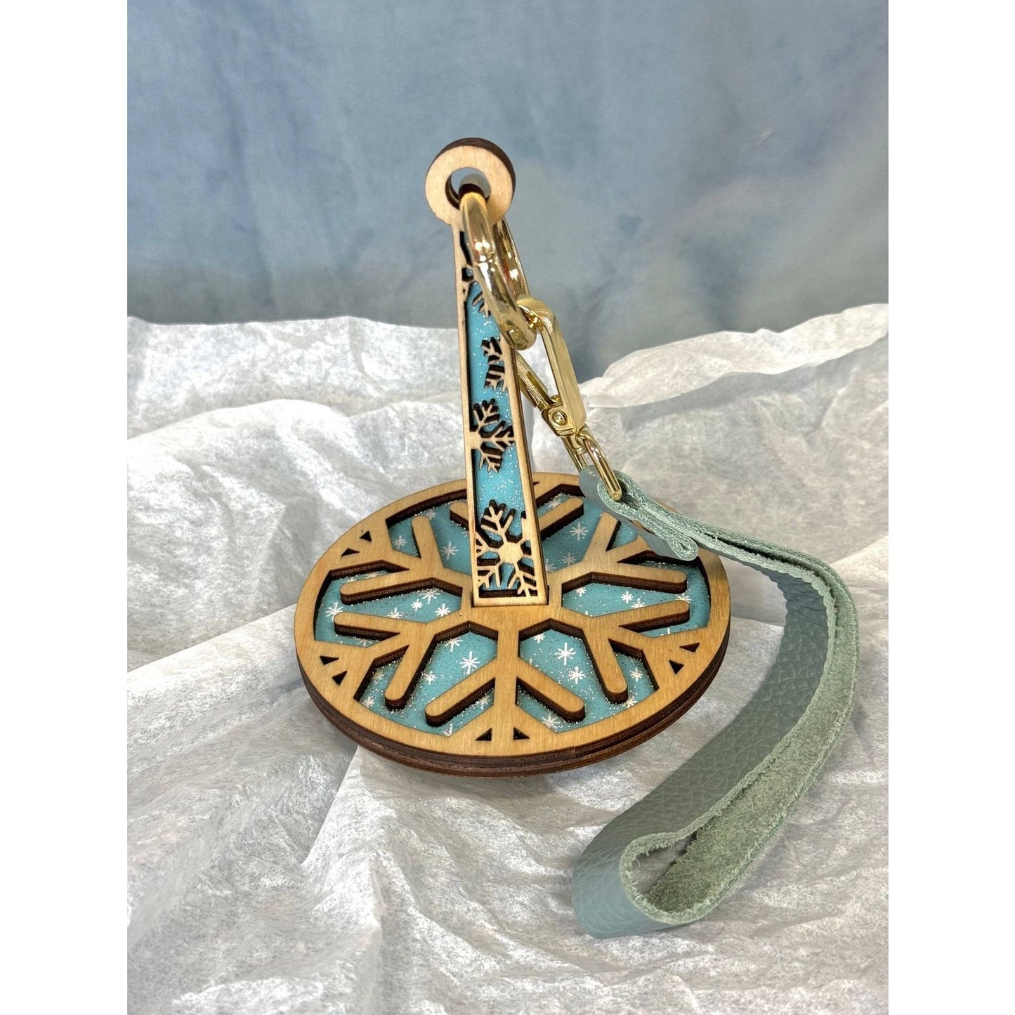 lemonwood snowflake yarn holder wooden snowflake disk with teal backing metal clip and leather wrist strap