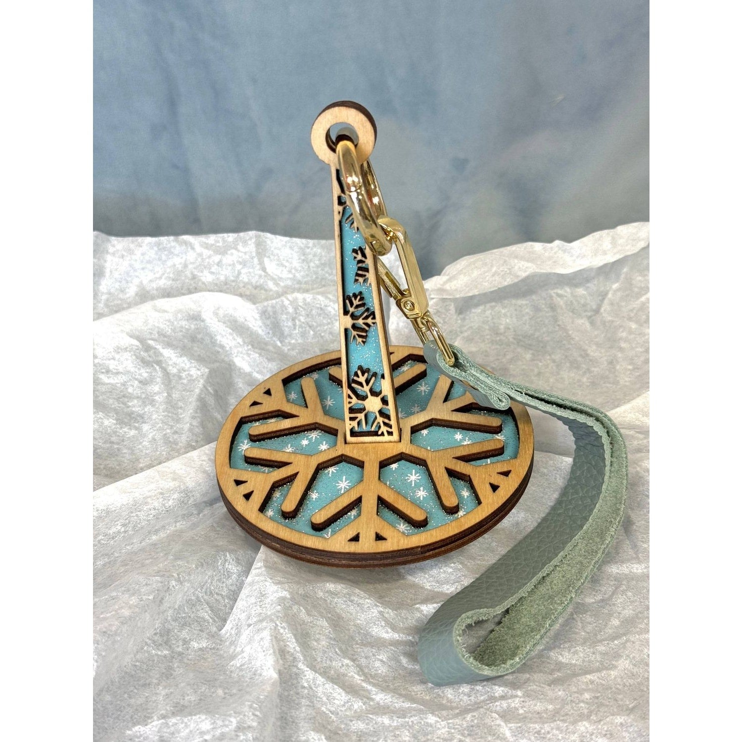 lemonwood snowflake yarn holder wooden snowflake disk with teal backing metal clip and leather wrist strap