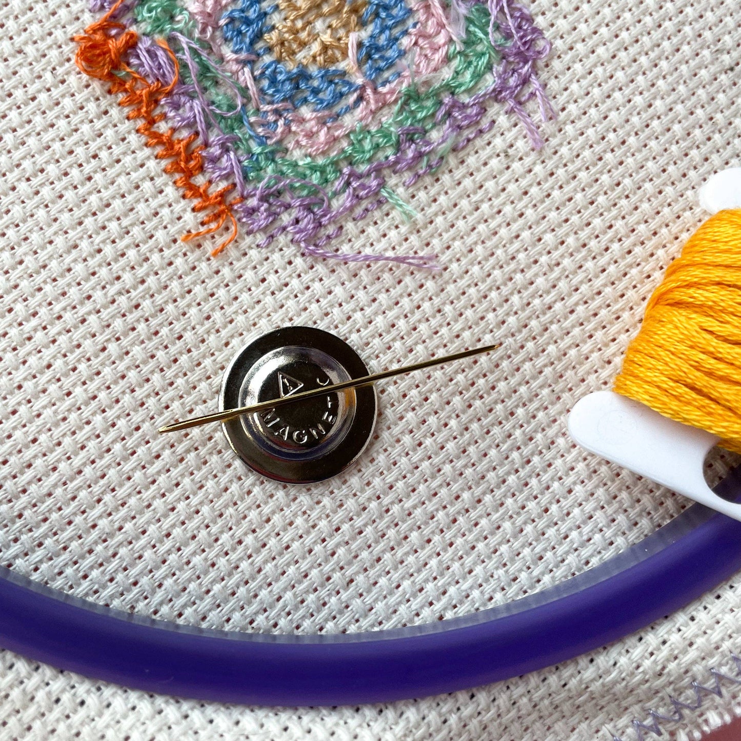 Close-up of embroidery thread, needle, and fabric showcasing witch-craft stitching techniques