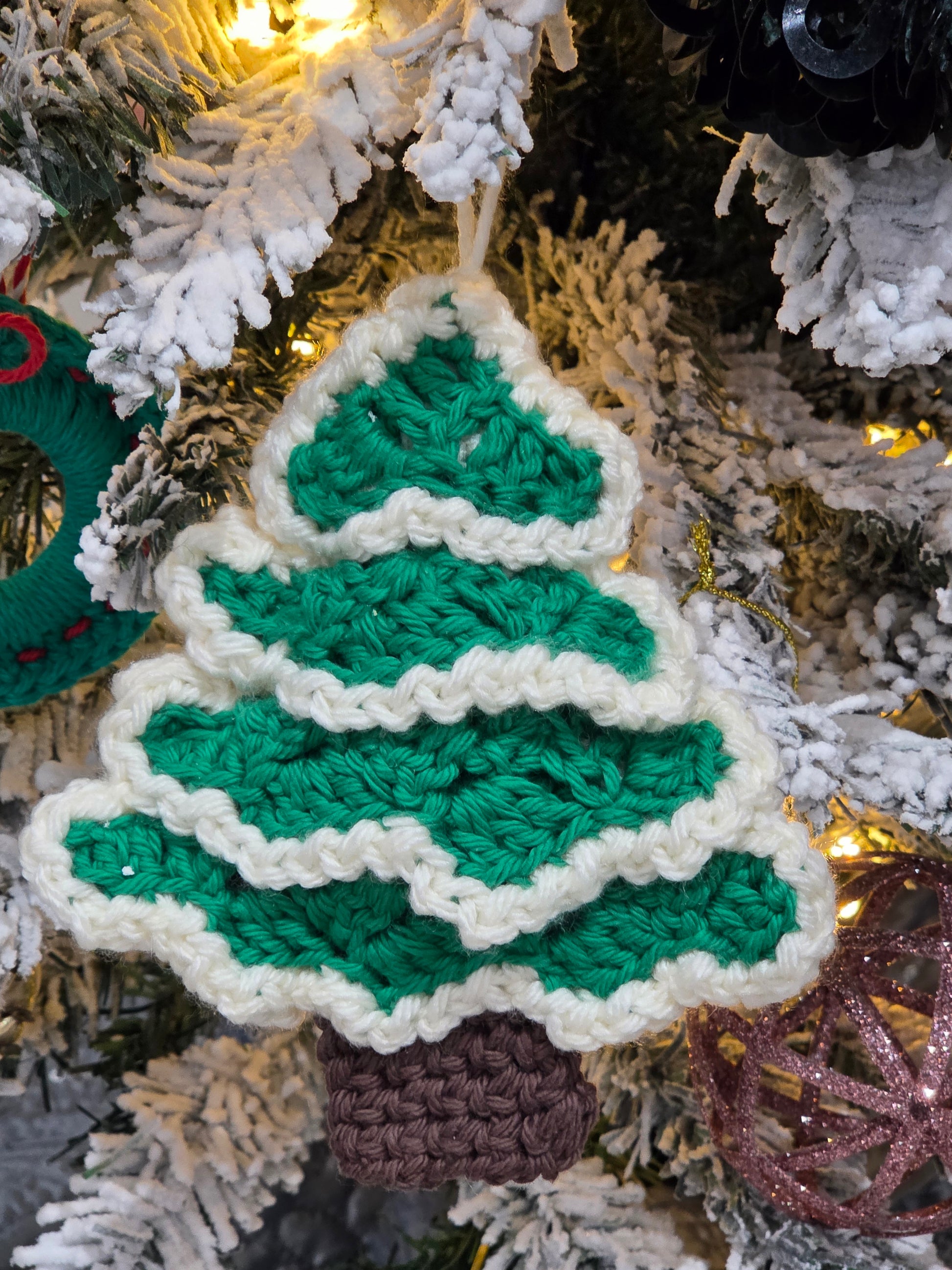 Crochet Christmas tree ornament workshop crafted decoration hanging on a snowy Christmas tree