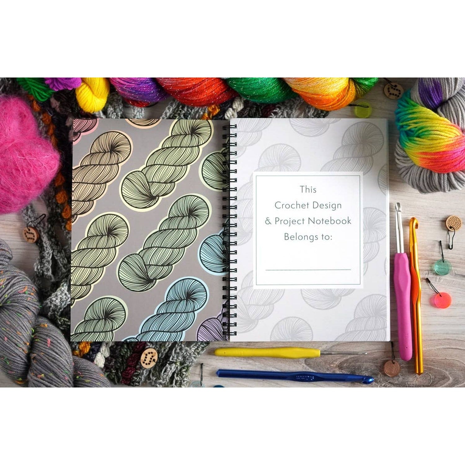 Crochet project journal for patterns with yarn and hooks by Bri Larson Art on wooden table