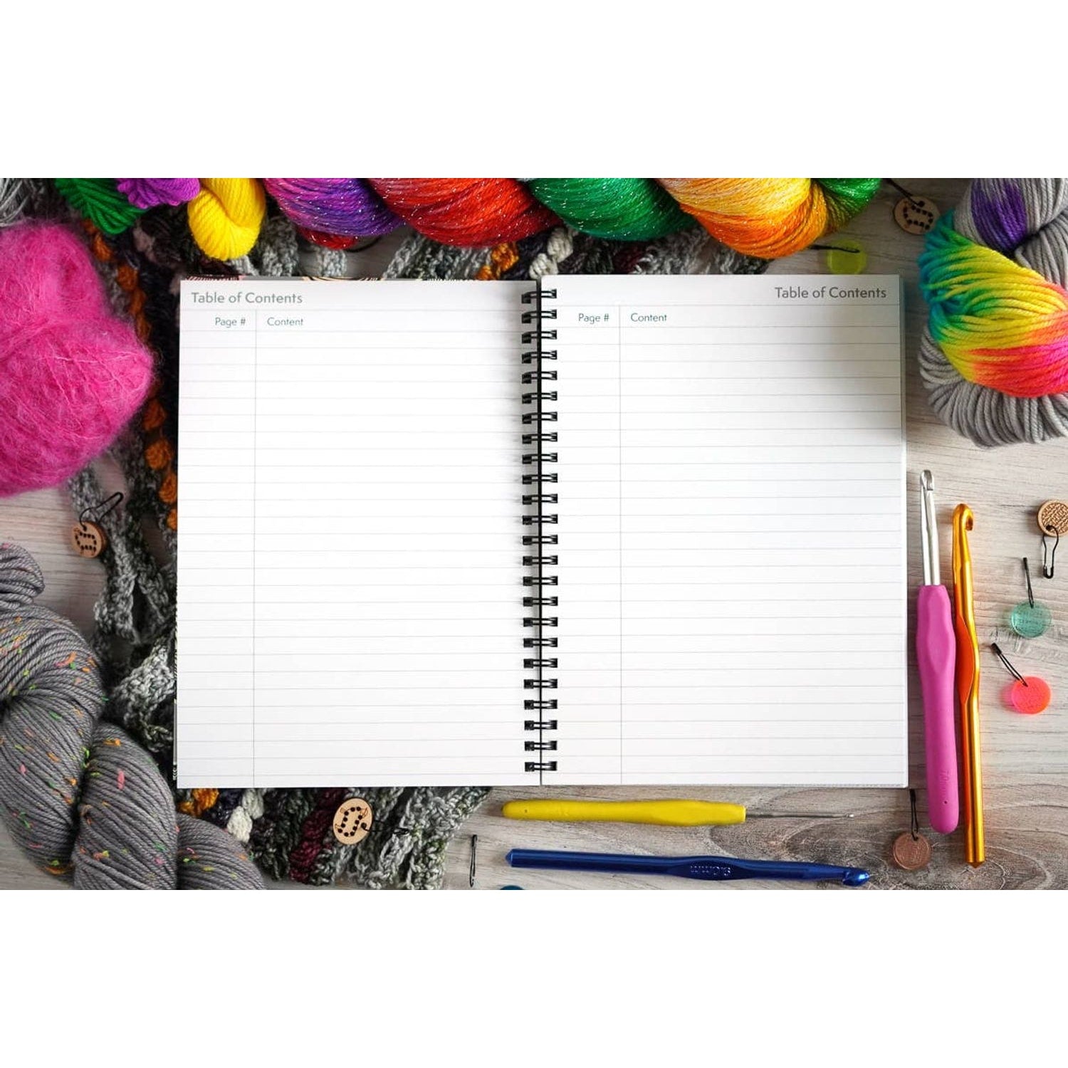 Open crochet project journal for patterns with blank table of contents pages surrounded by colorful yarn and crochet tools