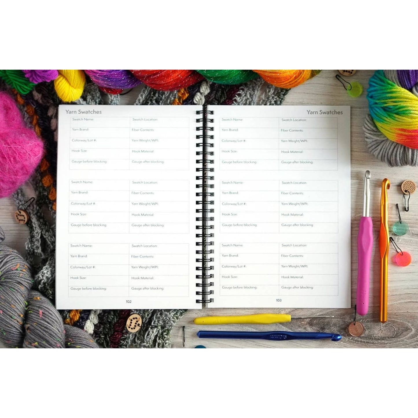 Open crochet project journal for patterns showing yarn swatches and tools surrounded by colorful yarns