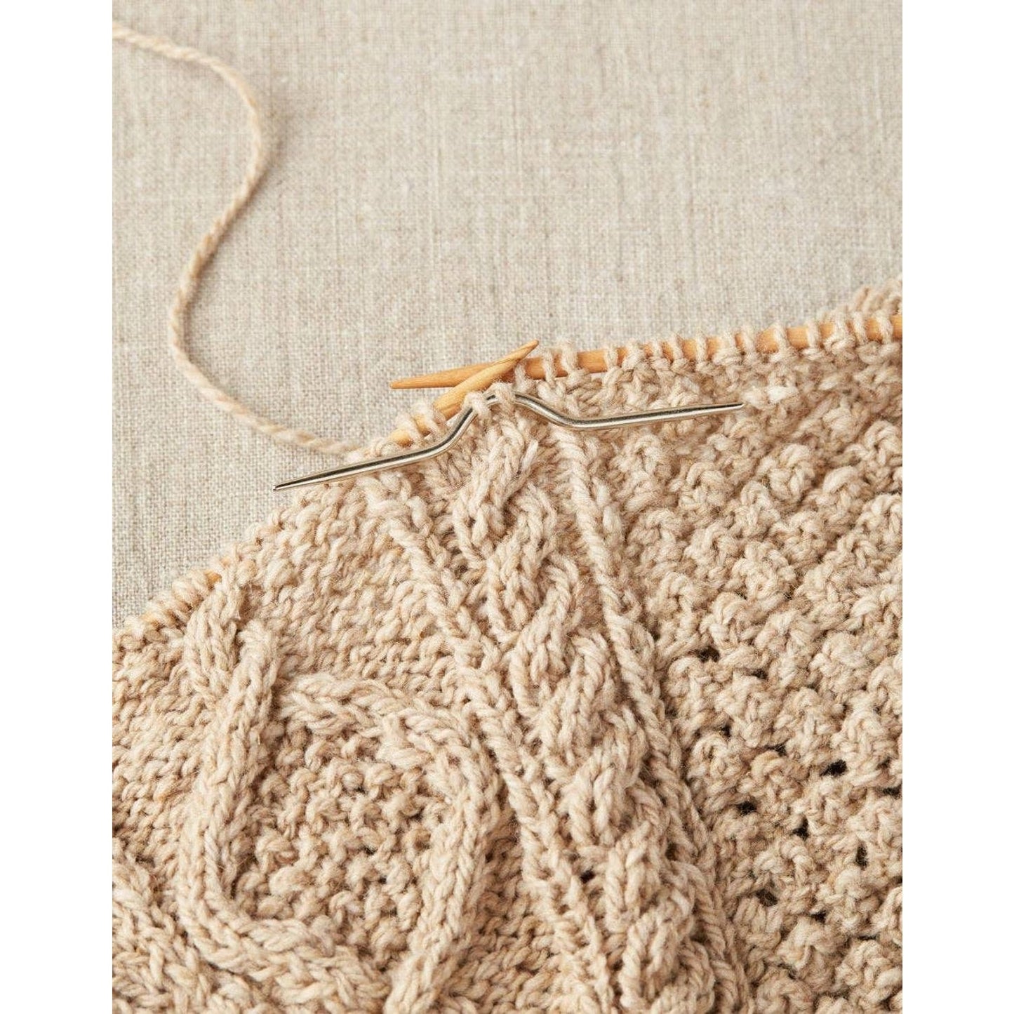 Cocoknits curved cable needles for knitting with a knitted beige fabric in progress