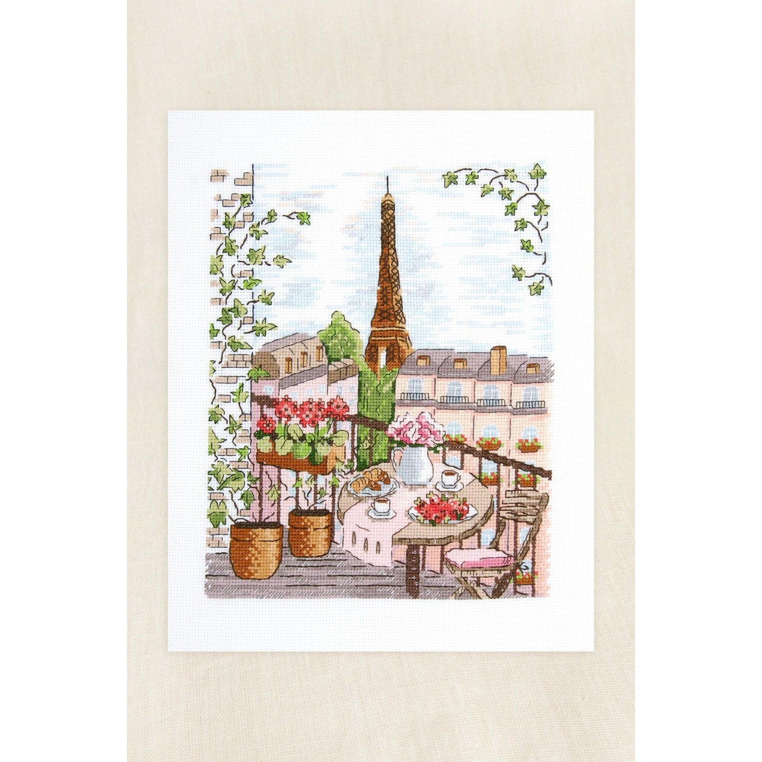 Beautiful cross-stitch art featuring a Parisian balcony with flowers and the Eiffel Tower Eiffel Tower in the background