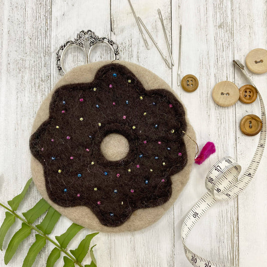 Handmade felt bag designed like a donut with colorful beads and sewing supplies