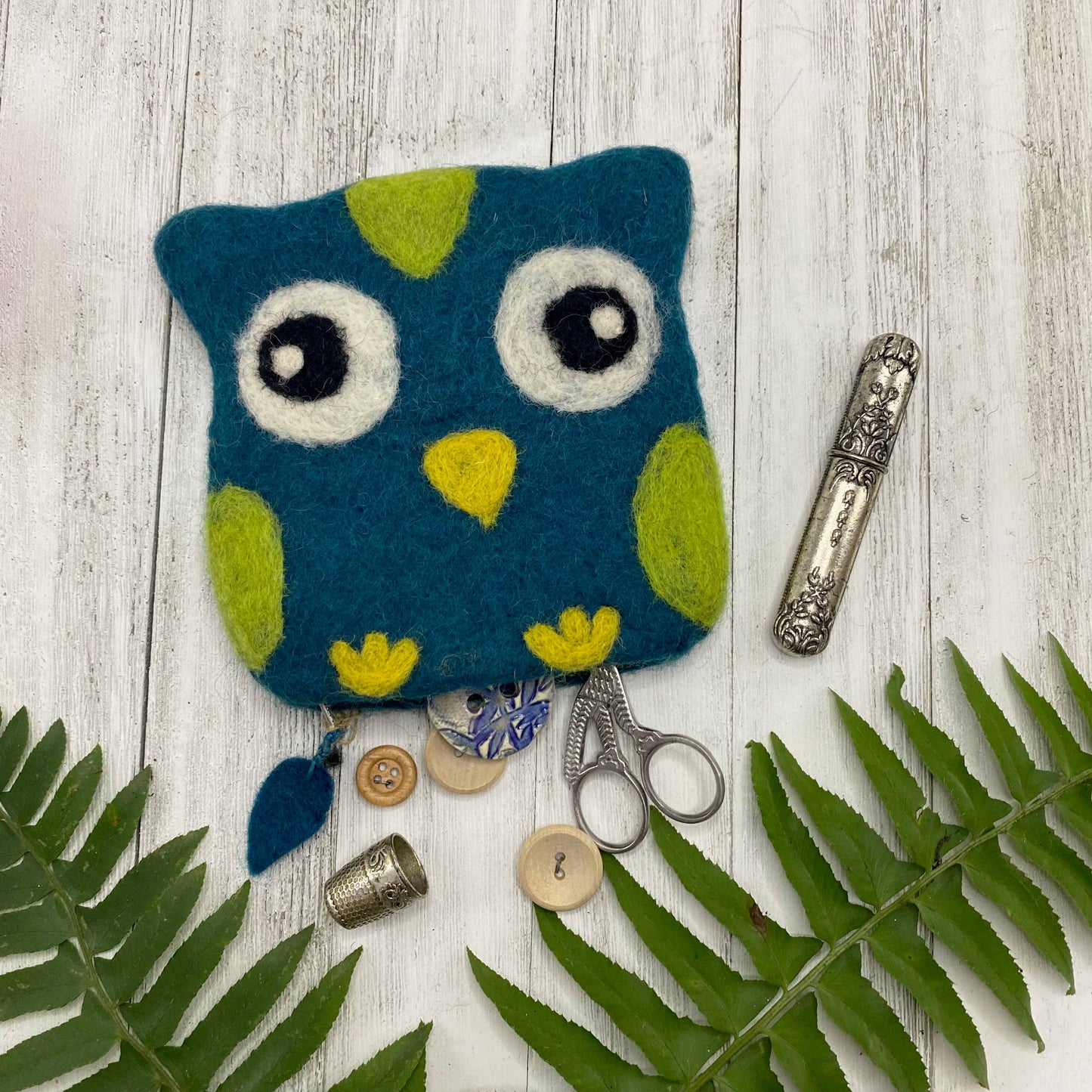 Colorful felt bag shaped like an owl with scissors and buttons inside, perfect for storage