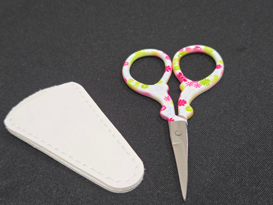 Amazon embroidery scissors with floral patterned handles and white protective case on black background