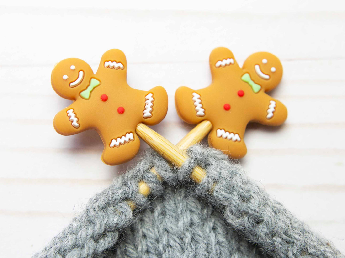 Fox & Pine Stitches point protectors gingerbread men on wooden needles holding gray handknit wool stitches