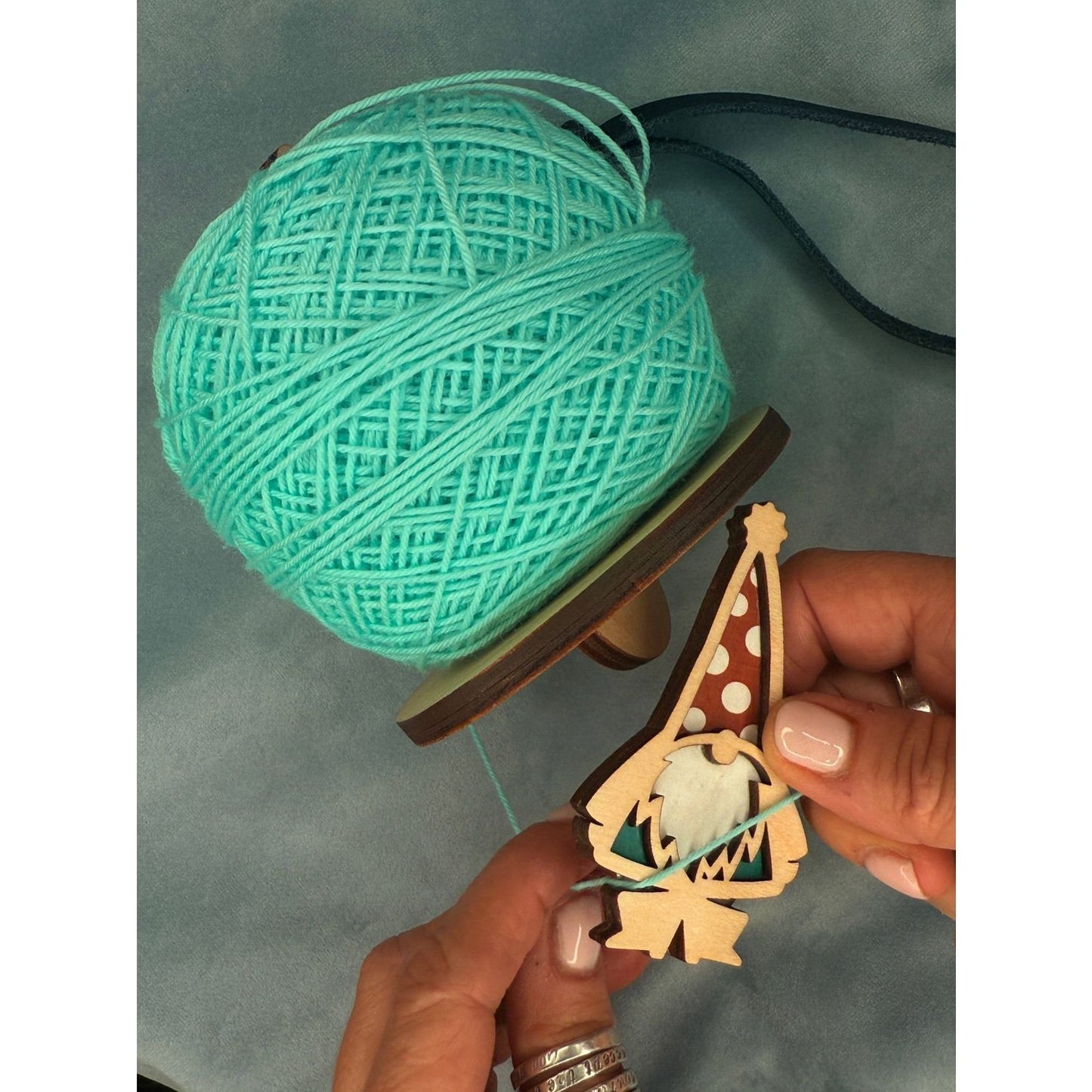 Crafting a garden gnome in garden with blue yarn and wooden design in hand