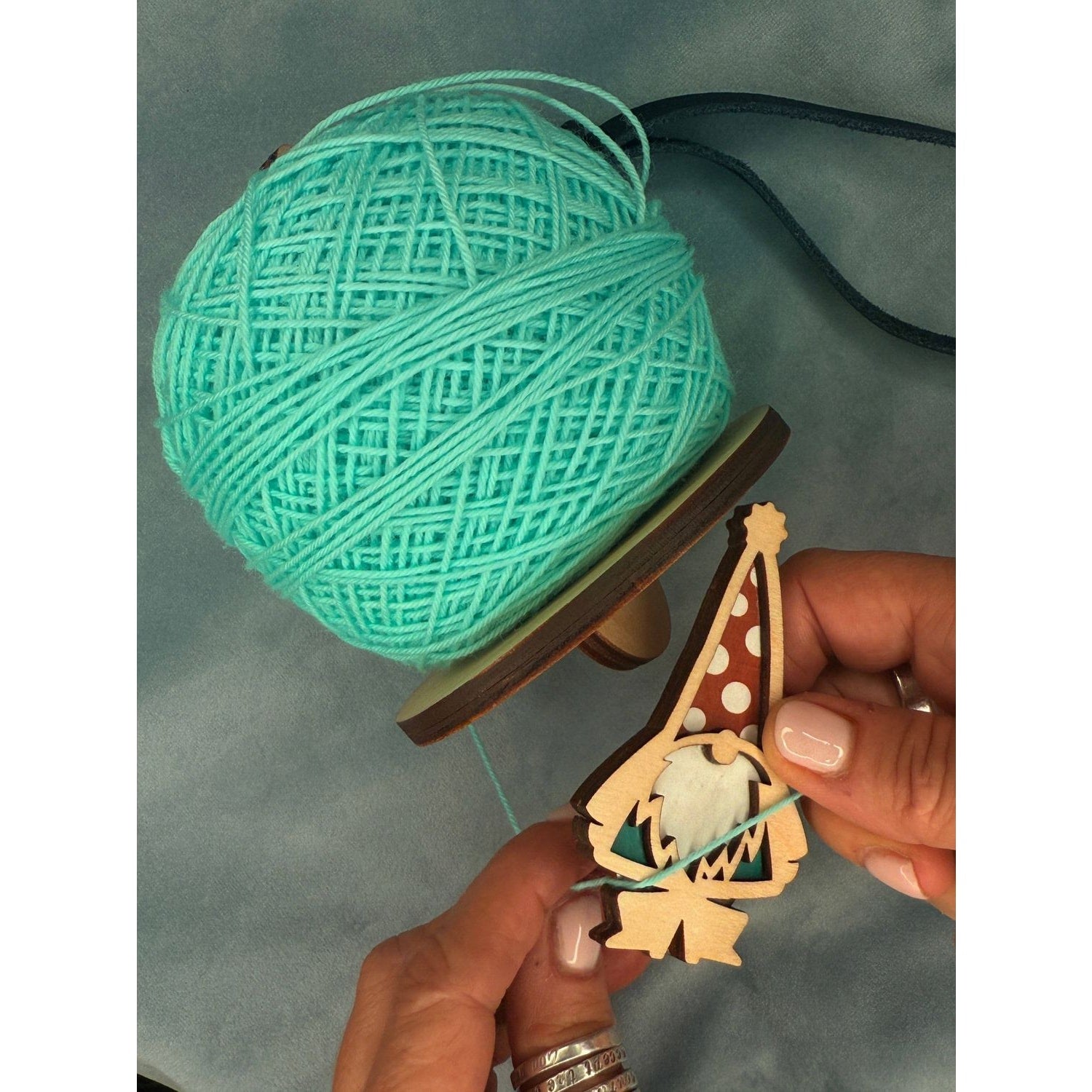 Crafting a garden gnome in garden with blue yarn and wooden design in hand
