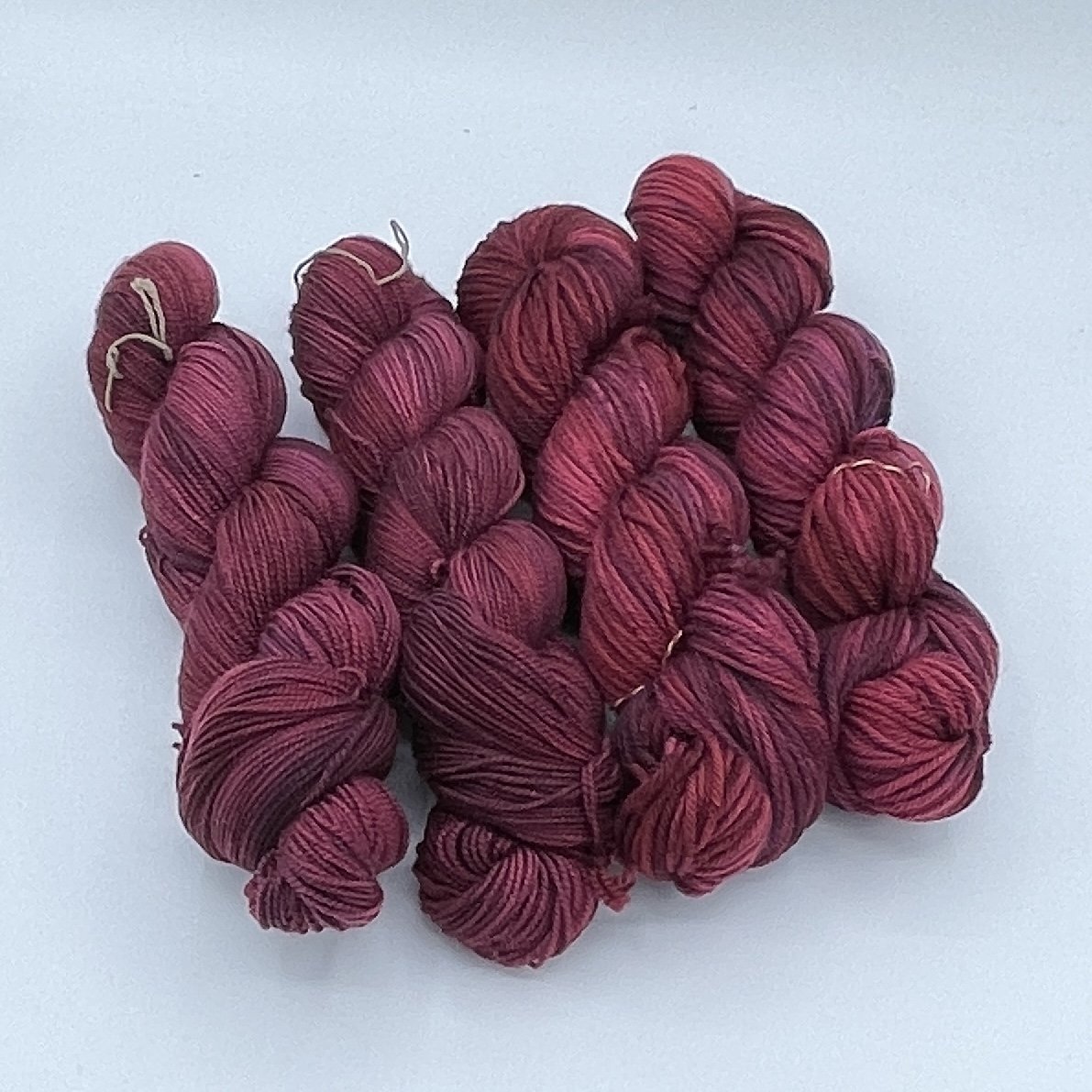 Gnome Depot Fiber DK weight yarn in shades of deep red and burgundy for knitting and crocheting projects