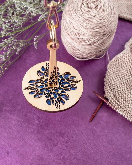 Lemonwood wooden yarn minder floral laser cut with blue resin inlay with yarn and knitting needles on purple background