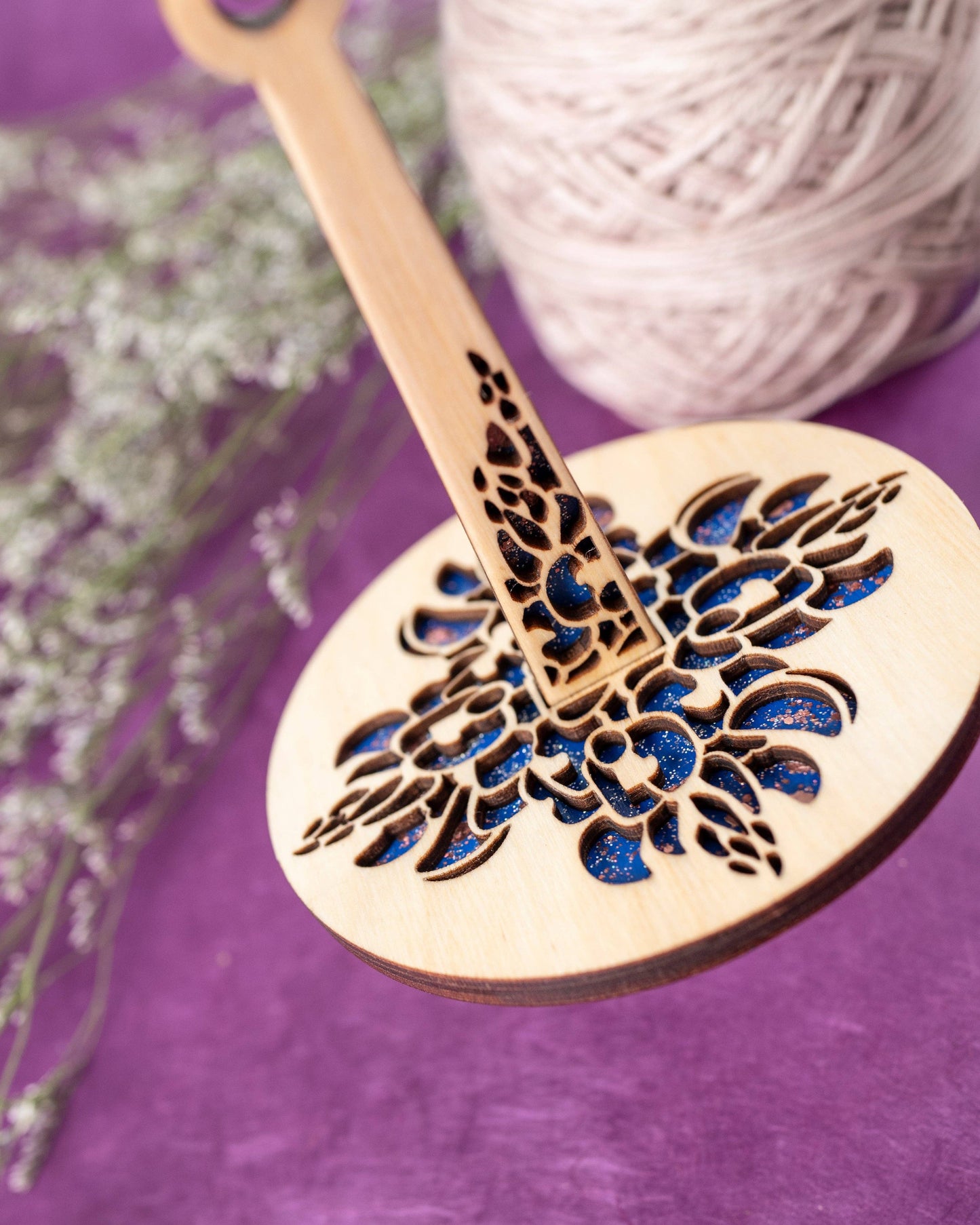 Lemonwood wooden drop spindle with laser cut floral pattern and blue resin inlay for hand spinning yarn