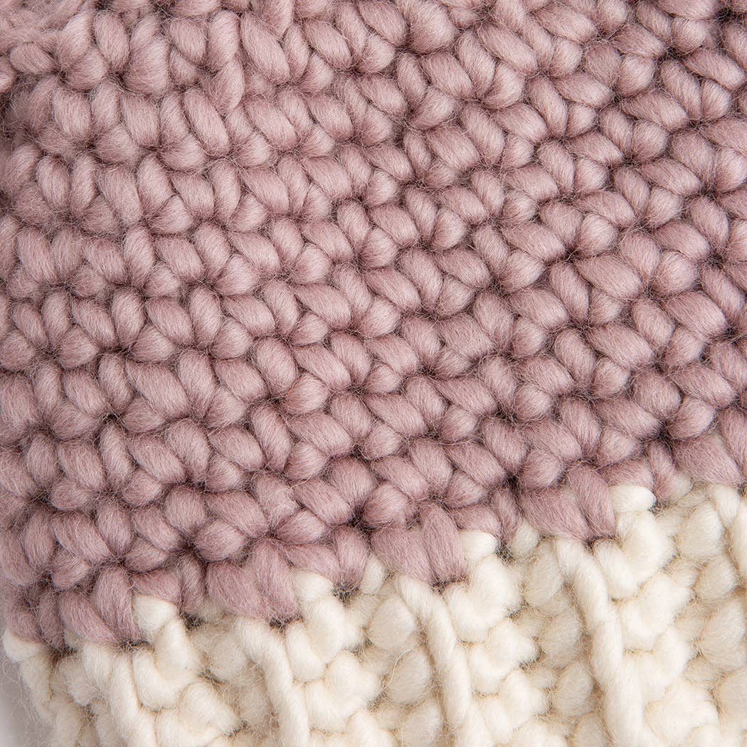 Close up of chunky pink and cream knit showing child wool bunny hat pattern texture and soft wool stitches