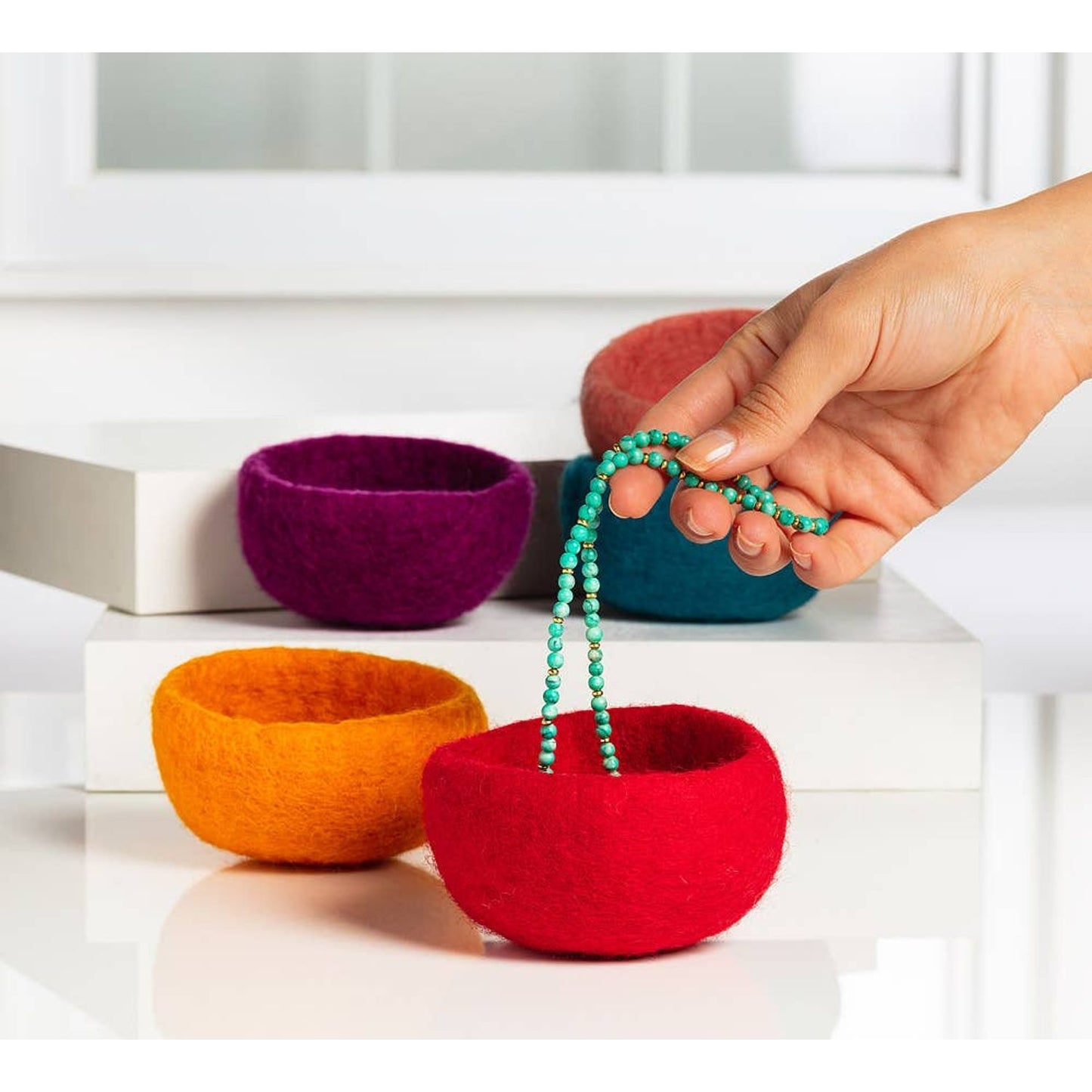 Colorful handmade yarn storage bowls in red, orange, purple, and pink for organizing craft supplies