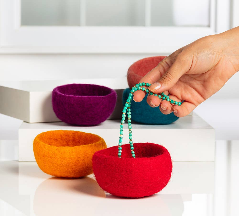 Colorful handmade yarn storage bowls in red, orange, purple, and pink for organizing craft supplies