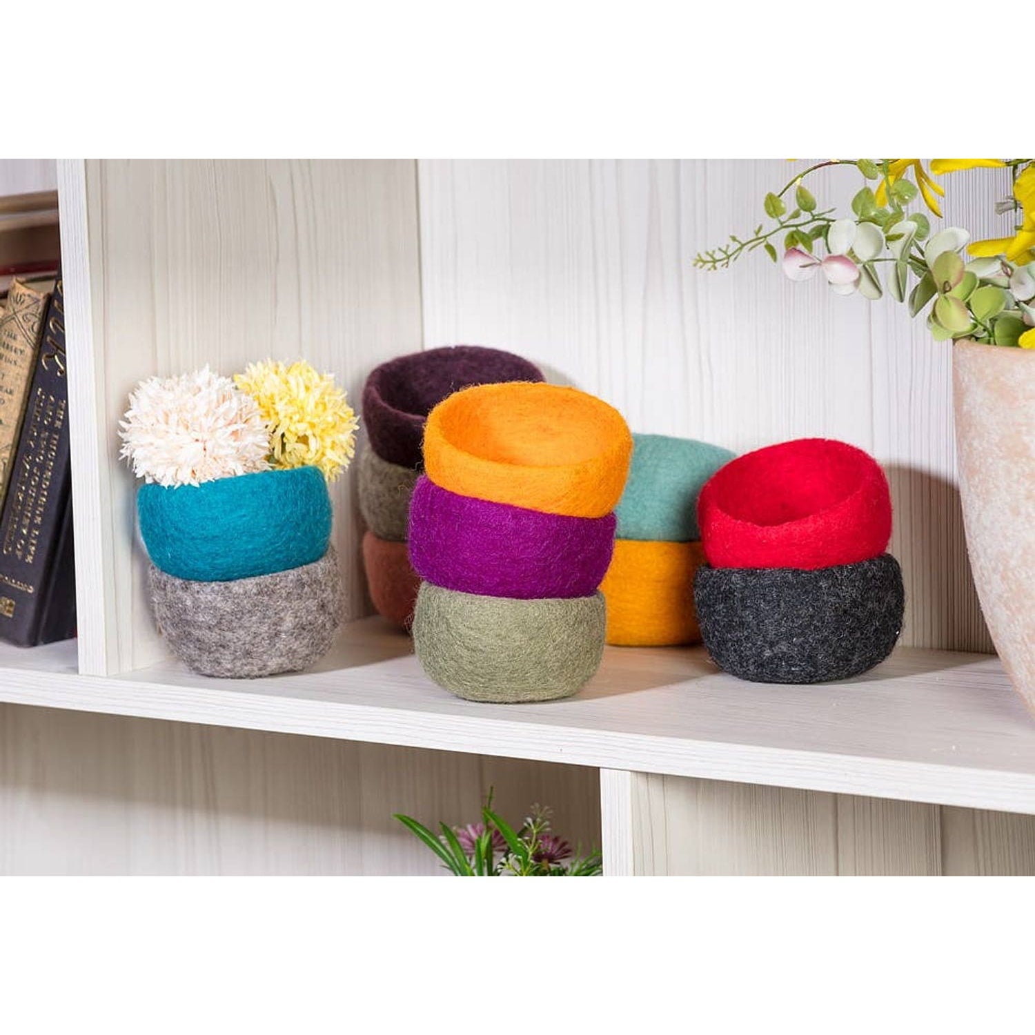 Colorful handmade yarn storage bowls stacked on a shelf for organizing yarn and crafts