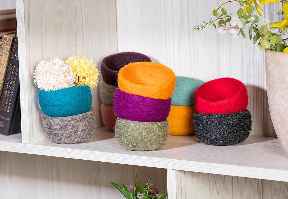 Colorful handmade yarn storage bowls stacked on a shelf for organizing yarn and crafts