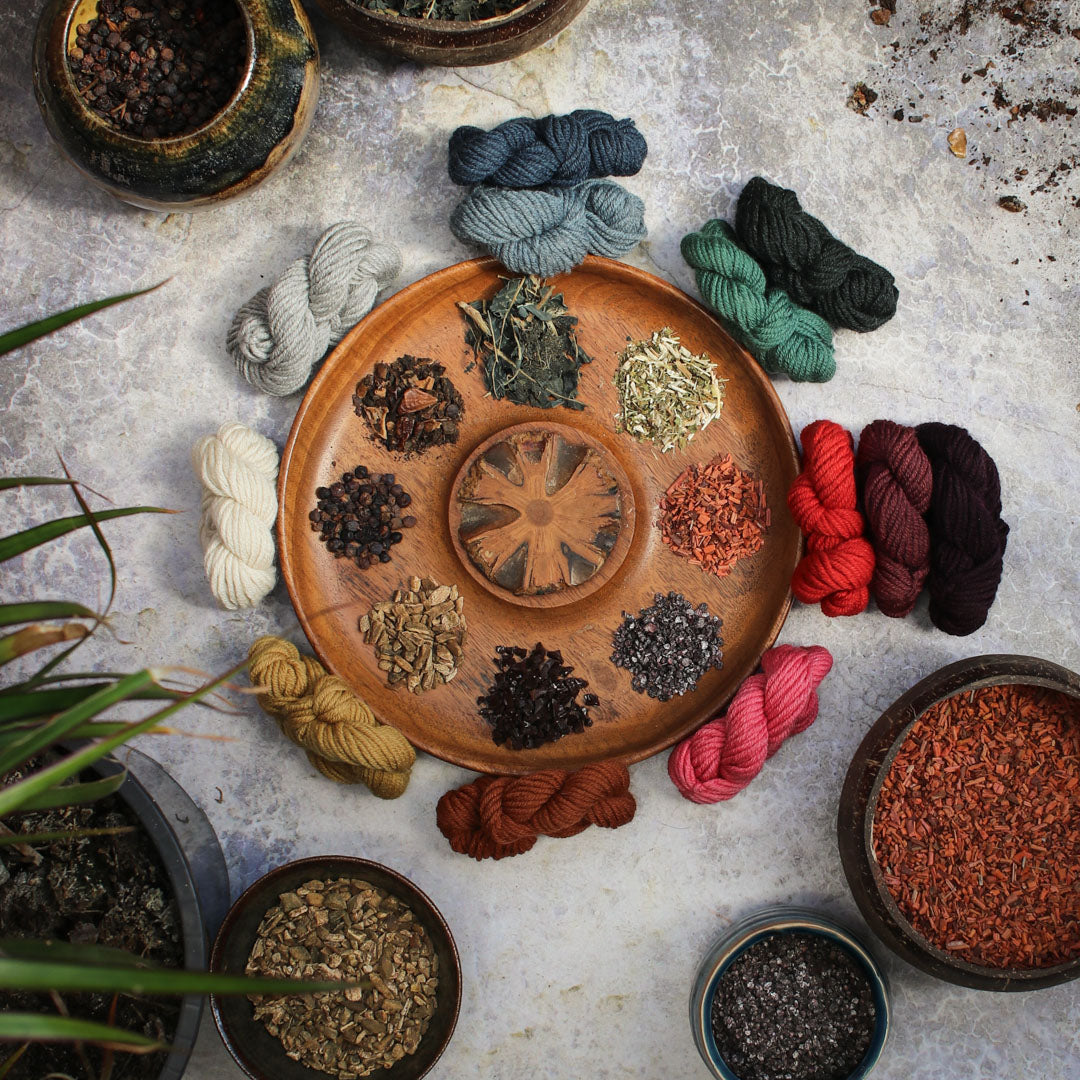 Herb & Hue yarn for knitting displayed in vibrant colors on a wooden plate surrounded by natural materials