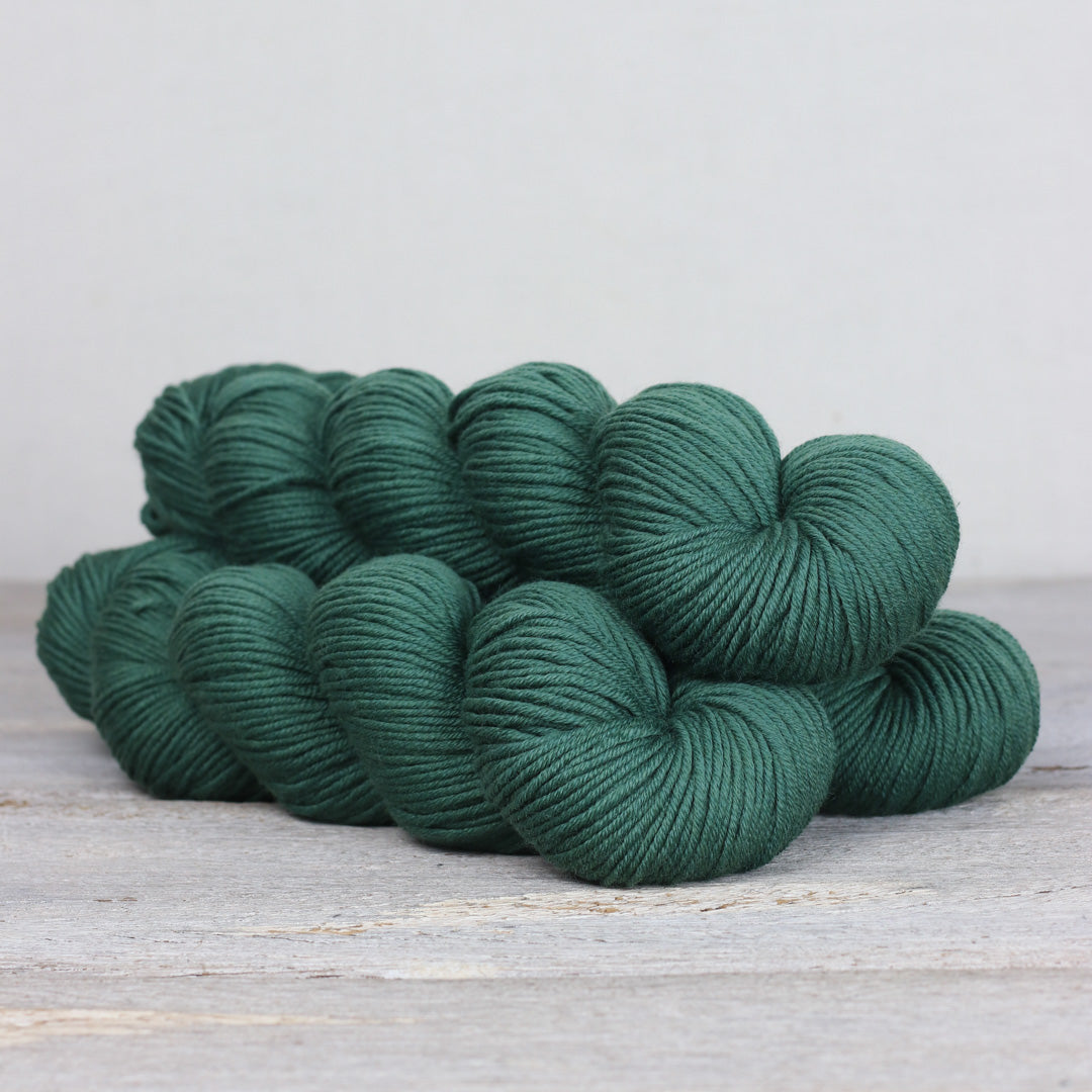 The Fibre Co. Herb & Hue yarn for knitting in deep green color arranged in soft skeins
