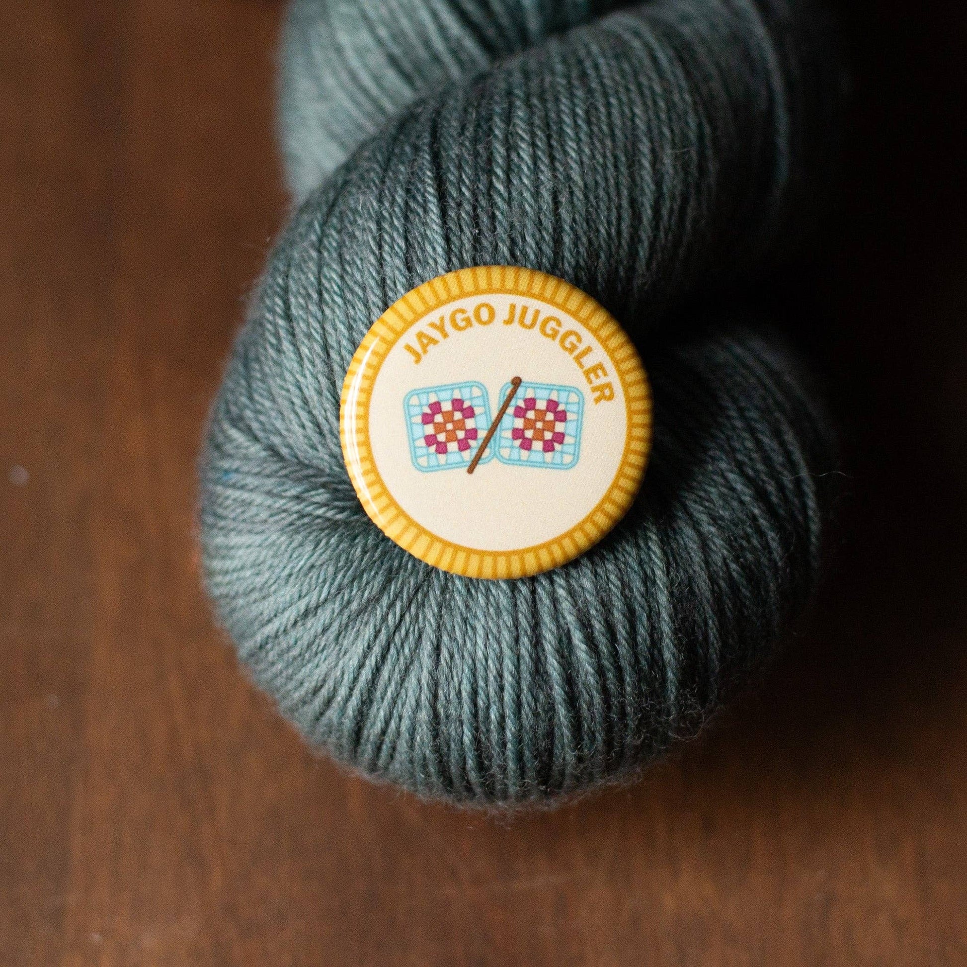 Camp Stitchwood Jaygo Juggler camp patch displayed on a skein of yarn