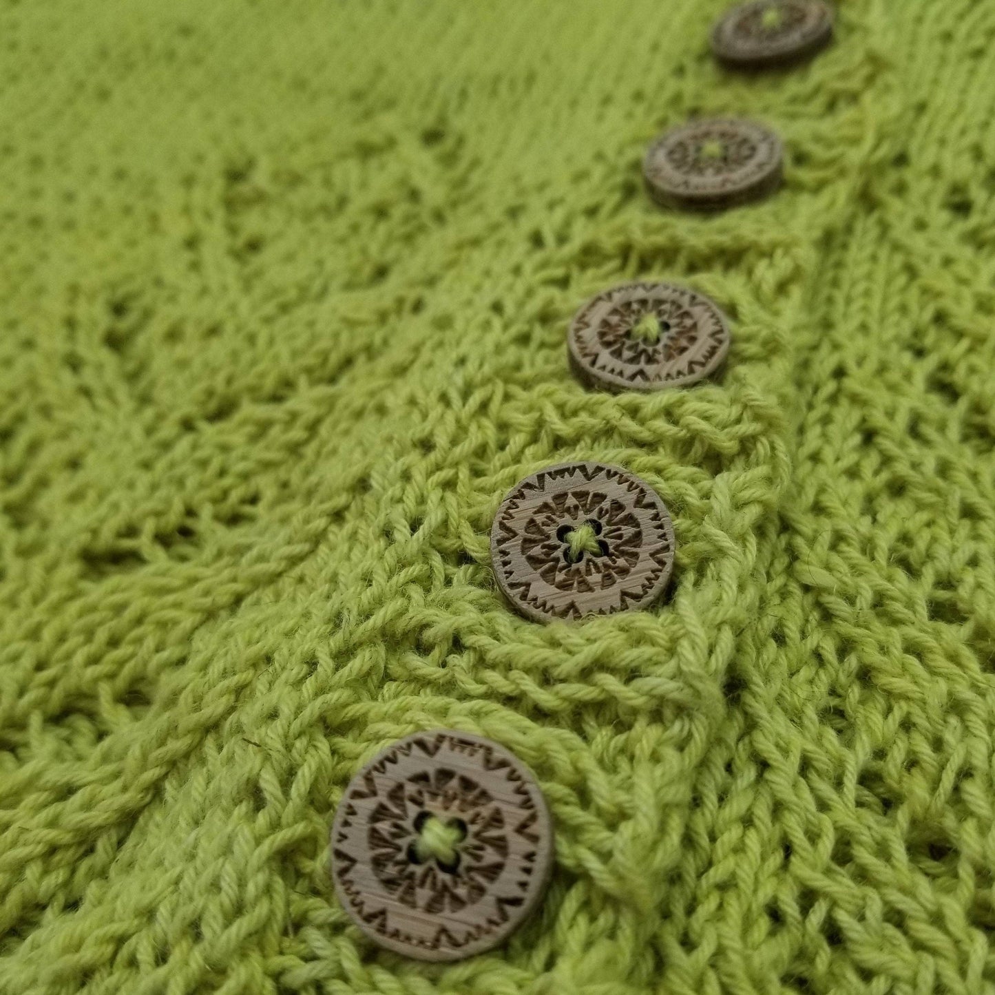 Katrinkles wooden buttons on a vibrant green knitted garment showcasing intricate design