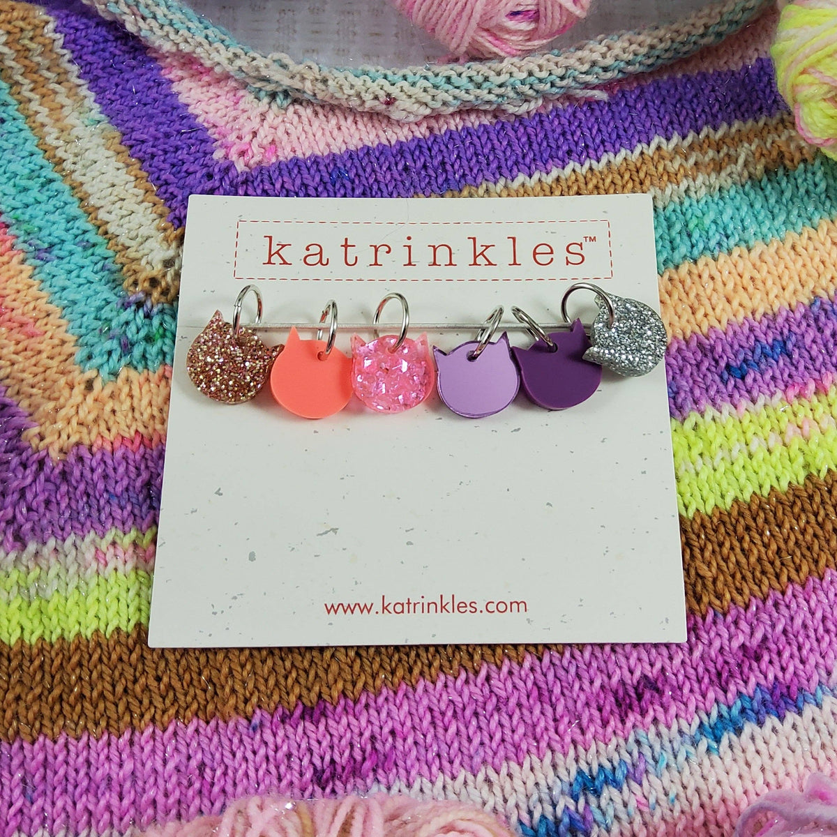 Colorful Katrinkles stitch markers for crocheting displayed on a card with vibrant yarn background