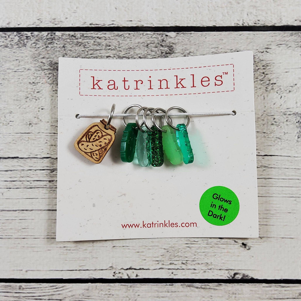 Katrinkles stitch markers for crocheting featuring glowing green designs and a wooden bread charm
