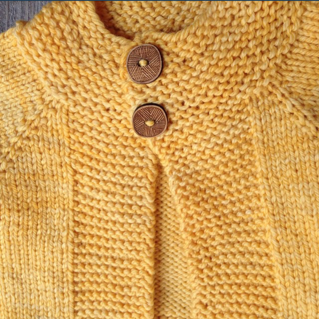 Close-up of a textured yellow cardigan with wooden buttons from Katrinkles