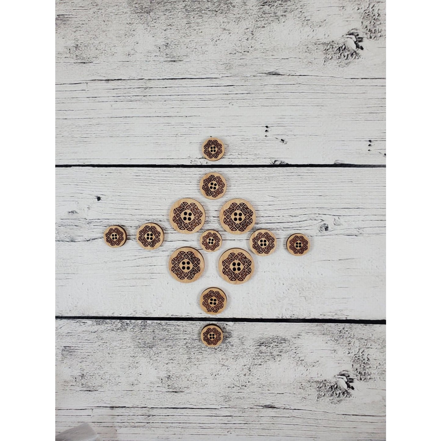 Katrinkles laser-cut wooden stitch markers in various sizes arranged on a white wooden background