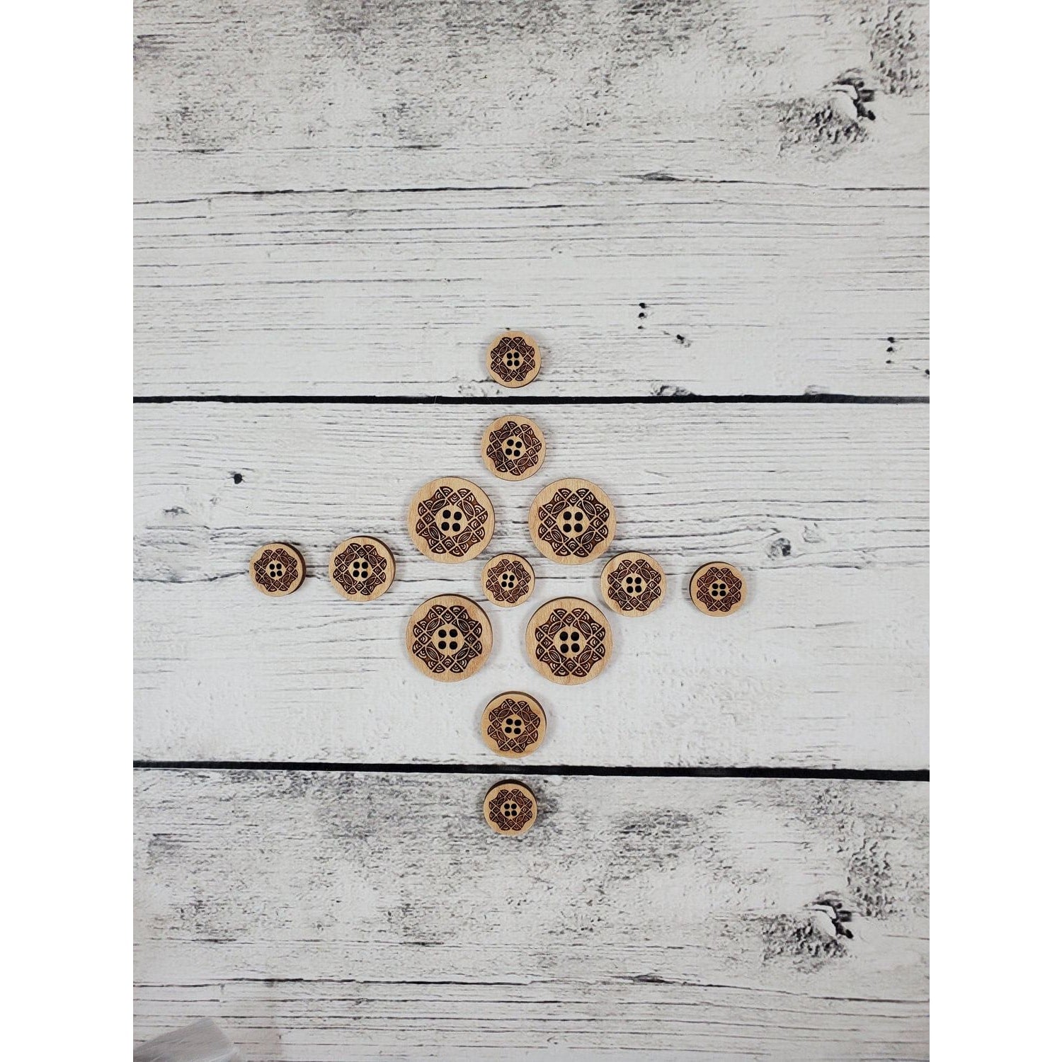 Katrinkles laser-cut wooden stitch markers in various sizes arranged on a white wooden background