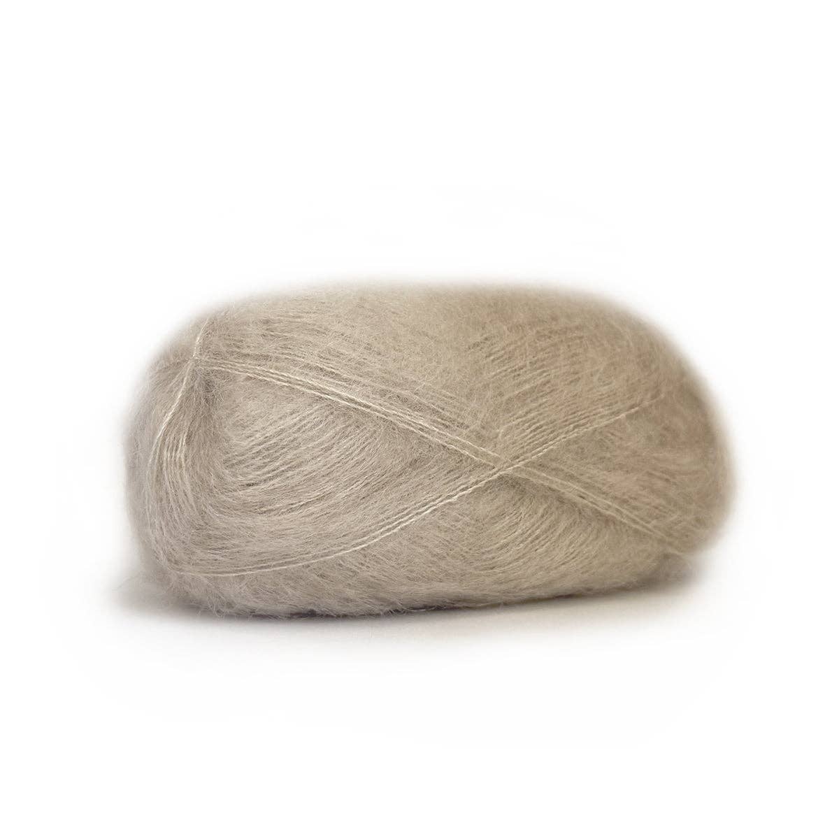 Soft beige Kelbourne Woolens Harmony yarn in a fluffy skein perfect for knitting and crocheting projects