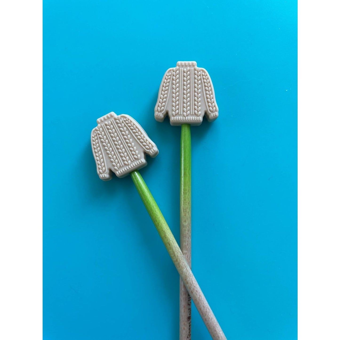 Cute sweater-shaped knitting needle point protectors in cream color for securing yarn projects