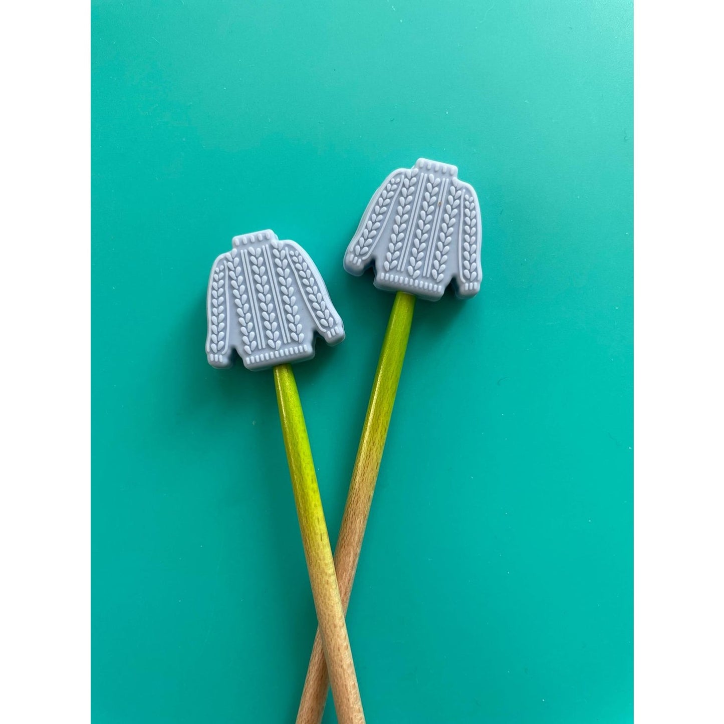 Knitting needle point protectors shaped like gray sweaters for safeguarding projects