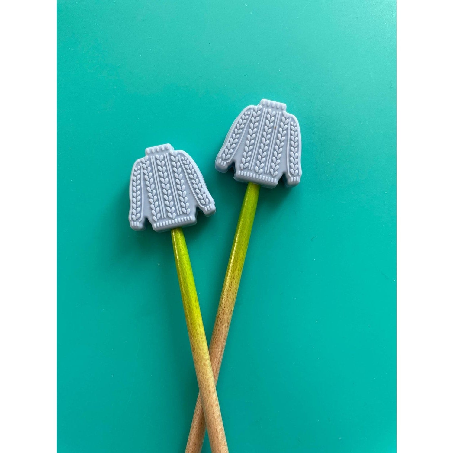 Knitting needle point protectors shaped like gray sweaters for safeguarding projects