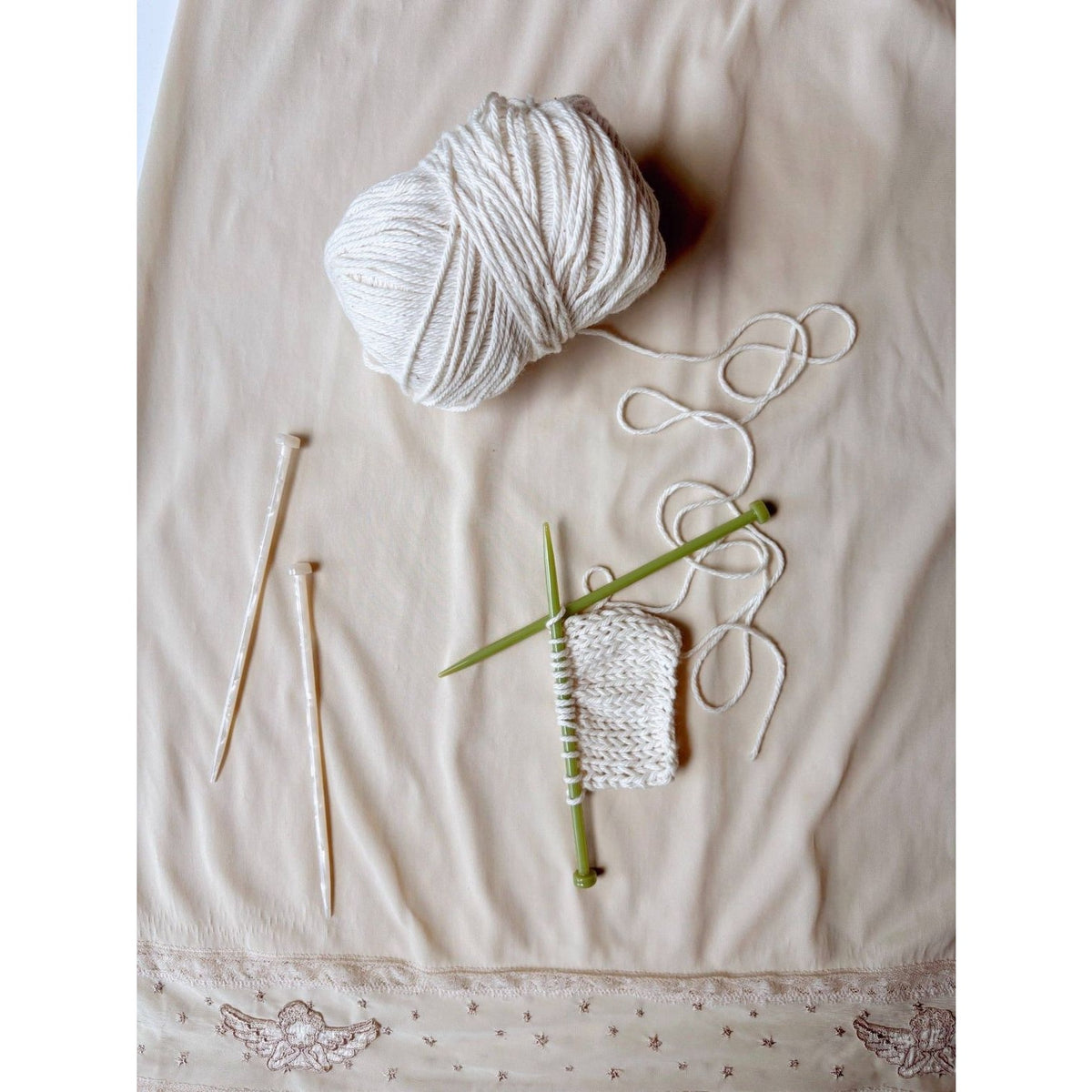 Hey Ricochet Hair Clip and knitting needles with white yarn on a soft background