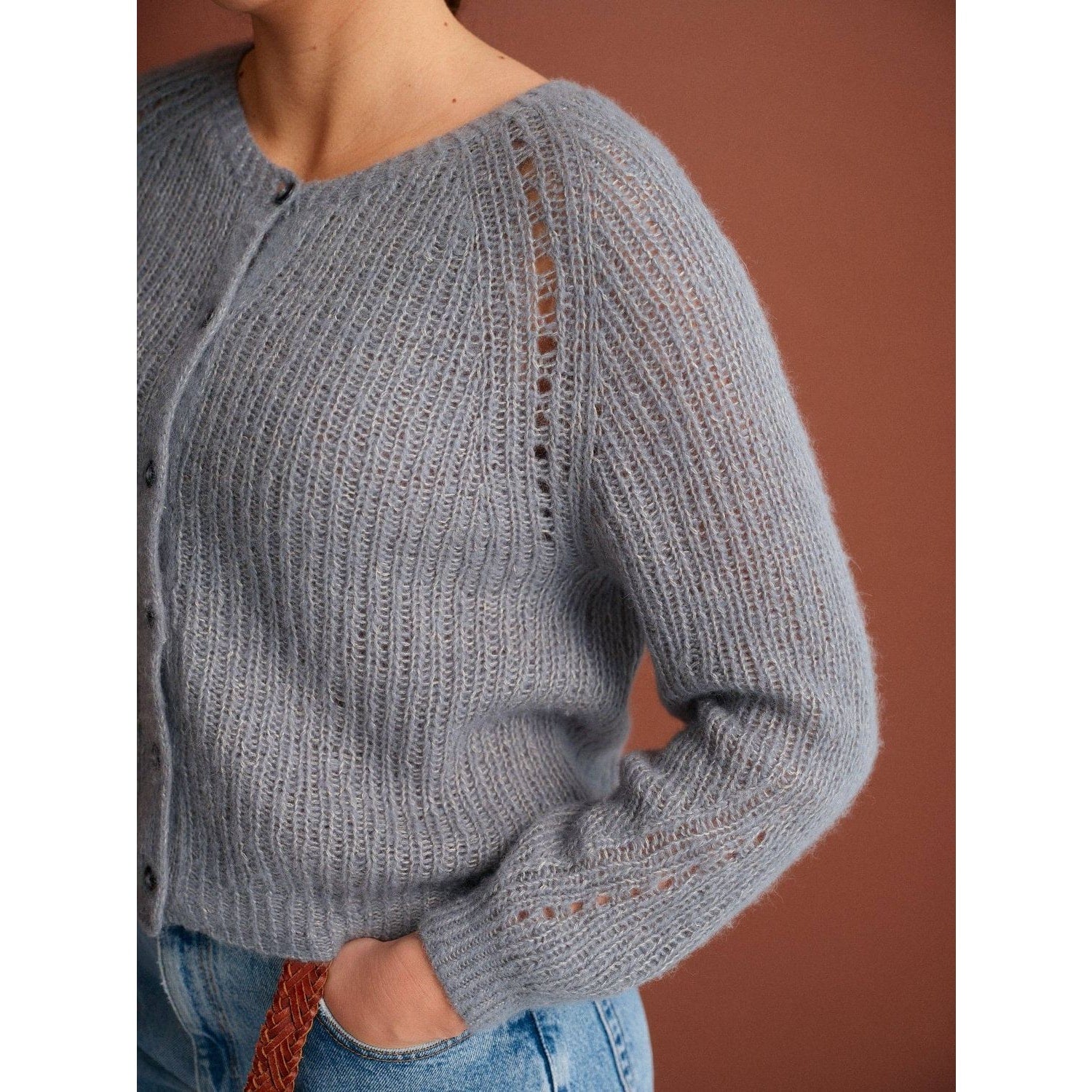 Light gray knitted cardigan with ribbed texture and button closure, featuring patterns in knitting