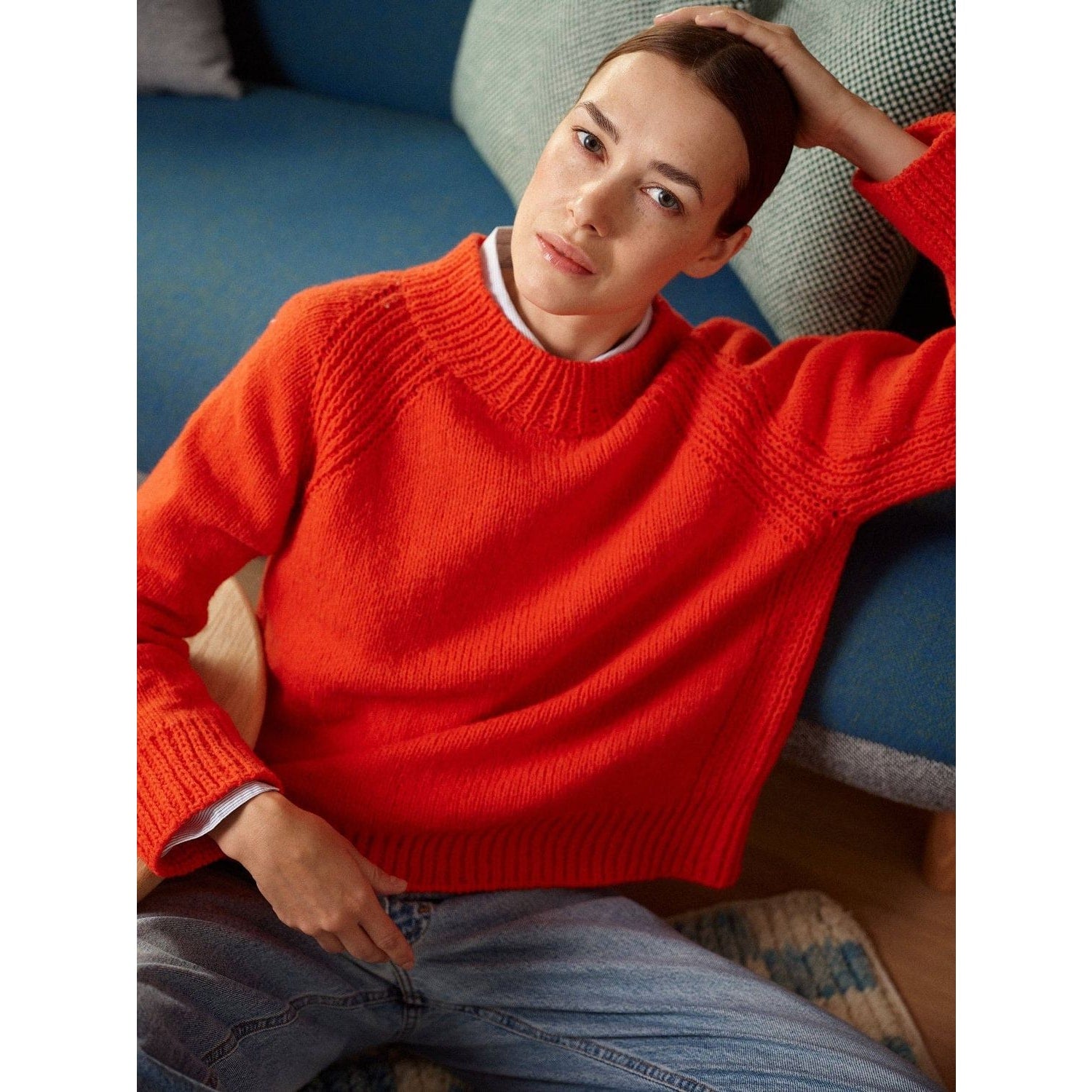 Bright orange knitted sweater showcasing modern patterns in knitting, worn casually with jeans
