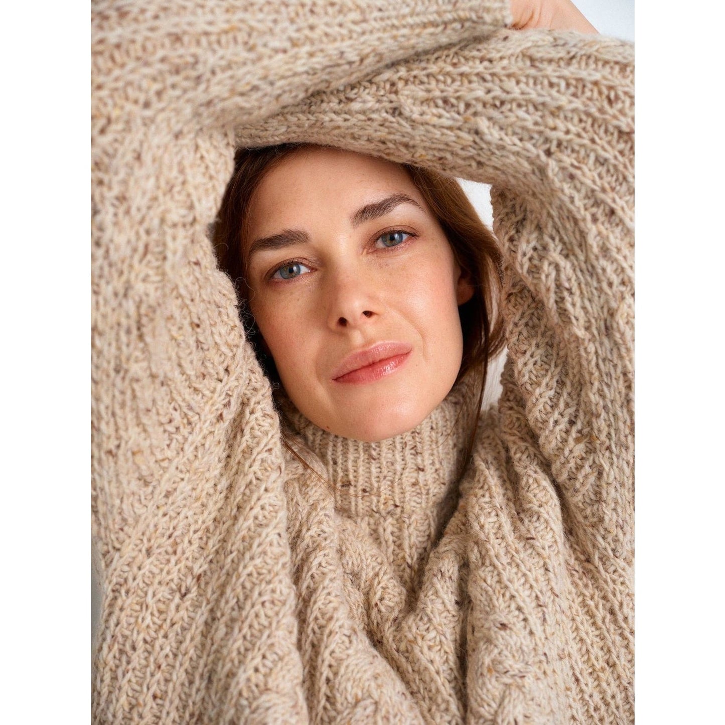 Cozy beige knitted sweater showcasing intricate patterns in knitting worn by a woman