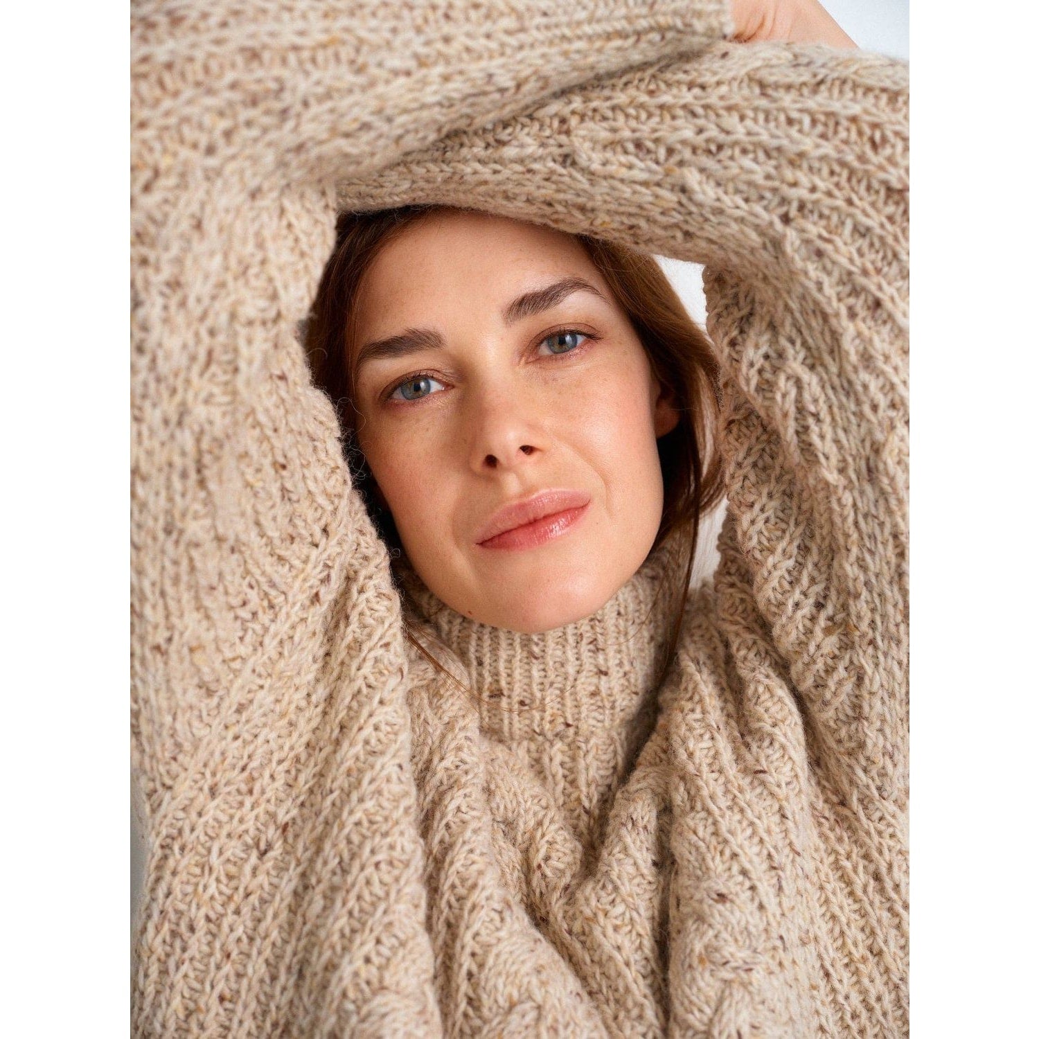 Cozy beige knitted sweater showcasing intricate patterns in knitting worn by a woman