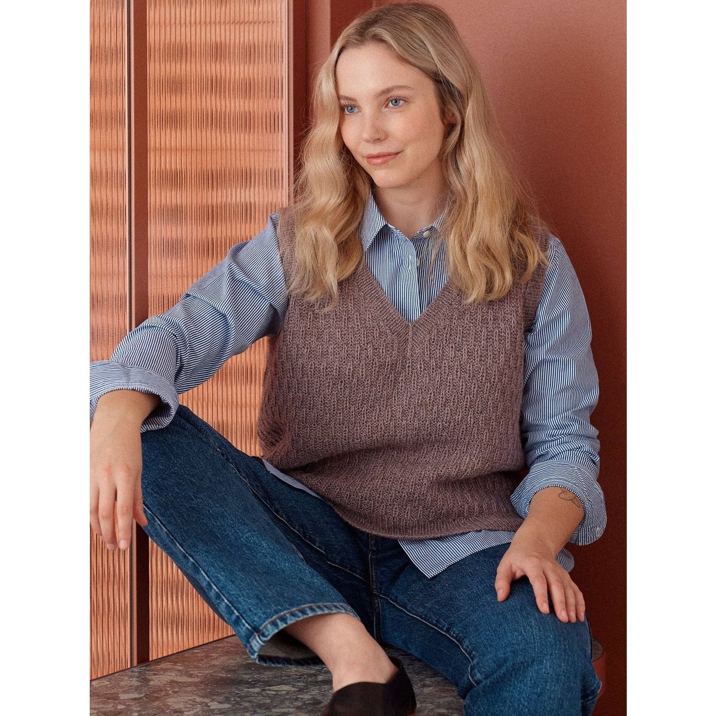 Fashionable knitted vest in mauve featuring intricate patterns in knitting, styled over a blue shirt