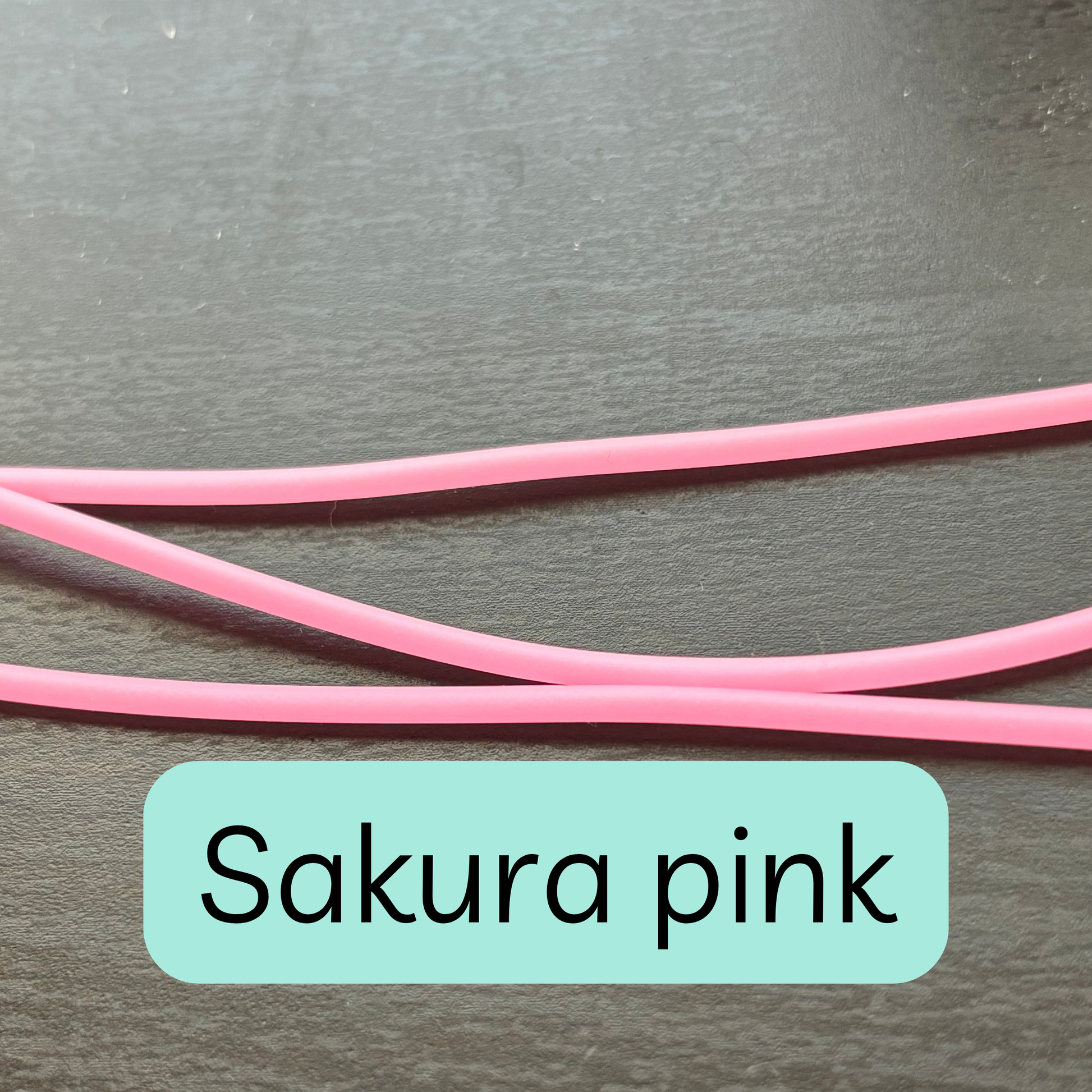 Sakura pink knitting tools by Comma Craft Co on a dark surface
