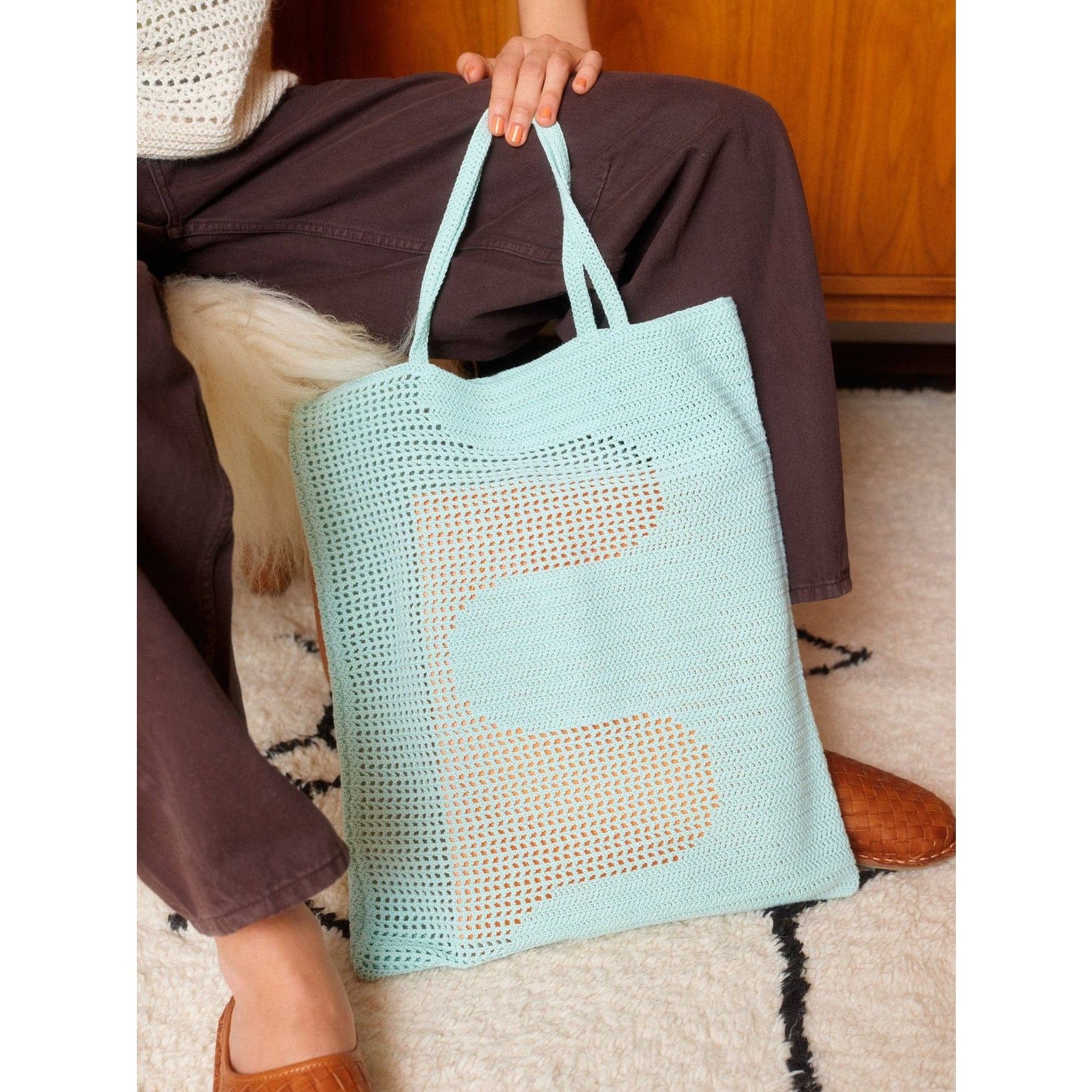 Light blue crochet tote bag with unique pattern, perfect for carrying essentials while crocheting with patterns