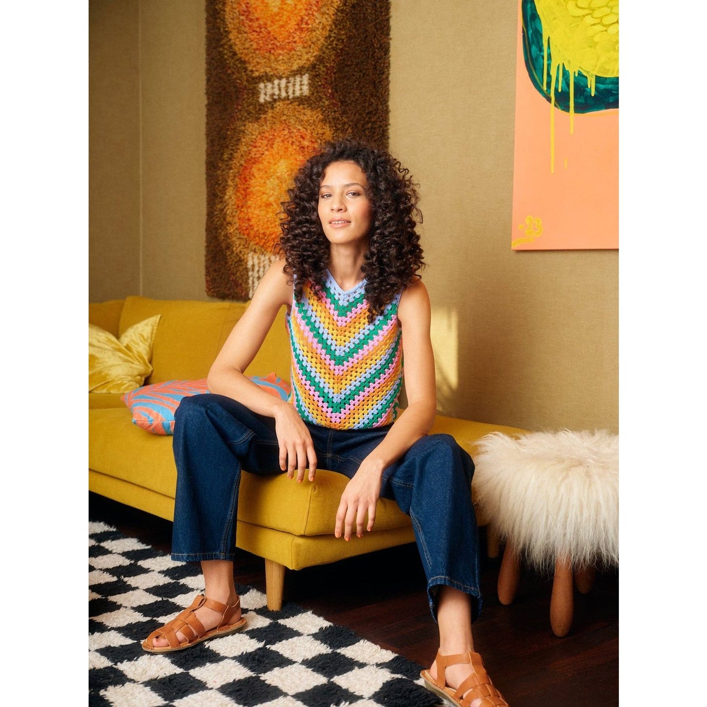 Colorful crochet top featuring patterns, styled with denim and set in a modern living room